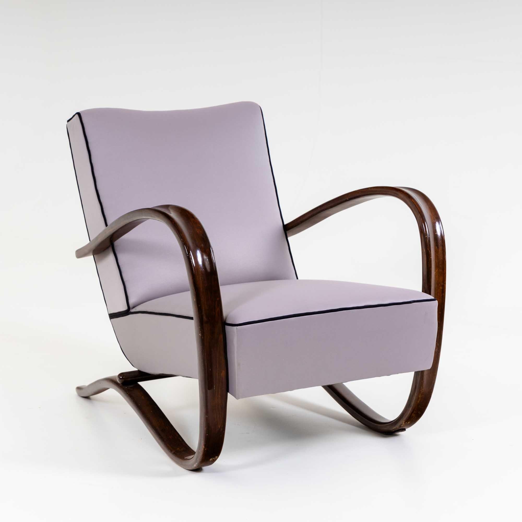 Fauteuil simple H-269 du designer tchèque Jindřich Halabala. Les accoudoirs, teintés dans la masse, suivent une élégante courbe en forme de C sur le côté du coussin d'assise et deviennent le cadre de soutien. Les chaises ont été récemment