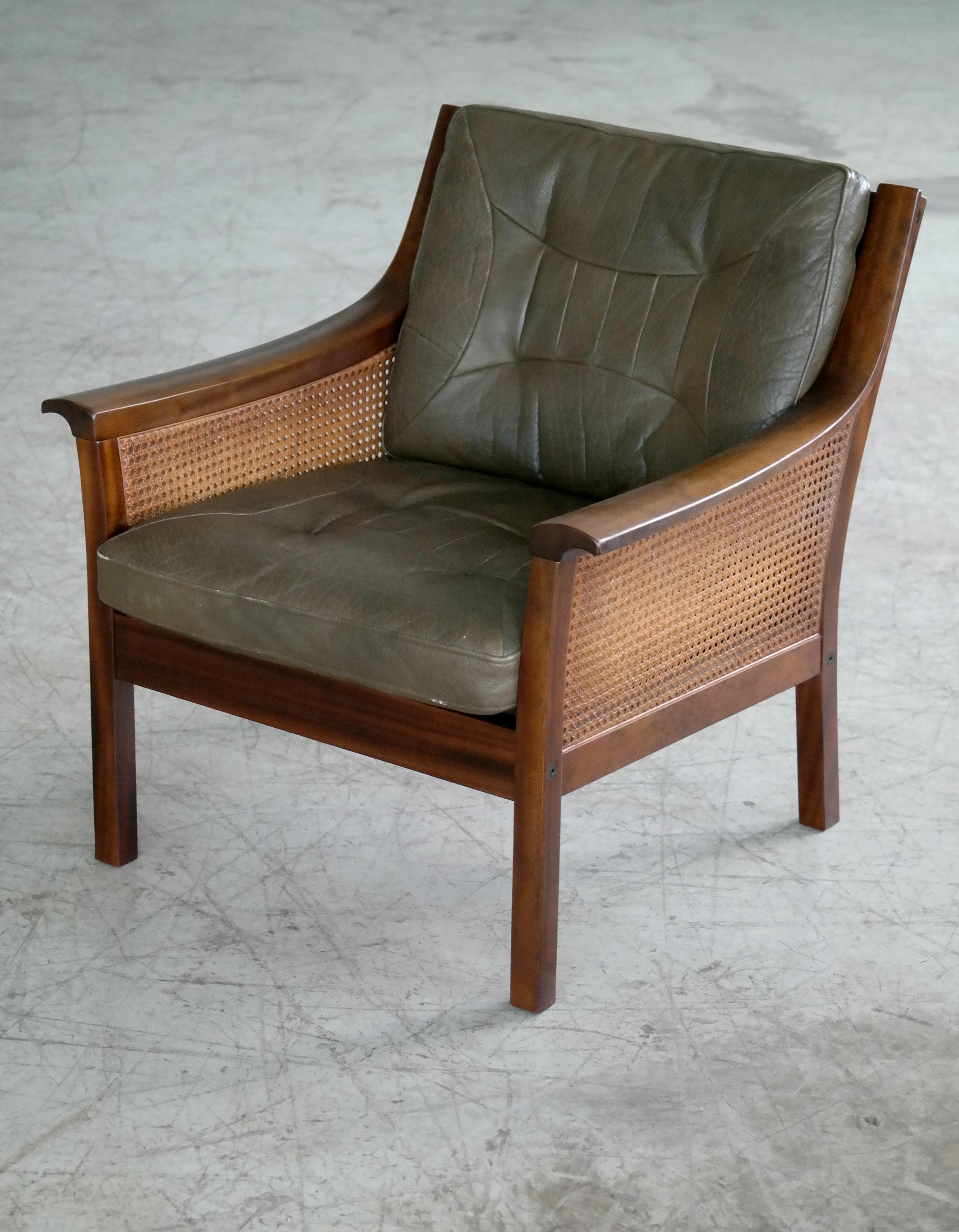 Beautiful lounge chair in stained beech with top grain olive colored leather cushions and woven double sided cane in the back and sides. Designed in the late 1960s by Torbjorn Afdal and produced by Bruksbo of Norway sometime in the 1970s. Both cane,