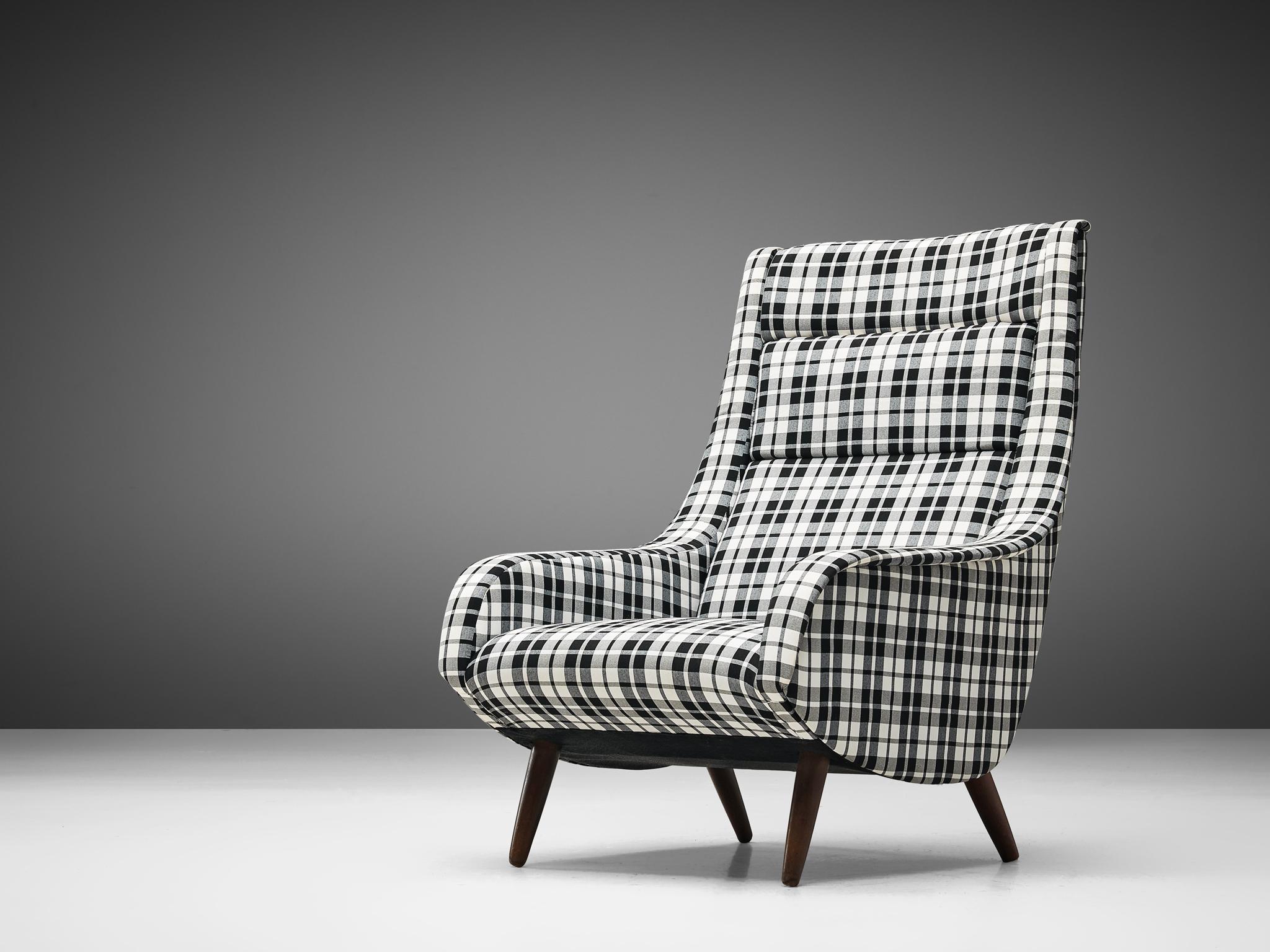 Lounge chair, fabric, wood, Denmark, 1960s
 
This easy chair invites you to spend more time on it due to the imposing, high backrest which is slightly tilted. The presence of armrests makes it possible to lay down your arms comfortably. The outer