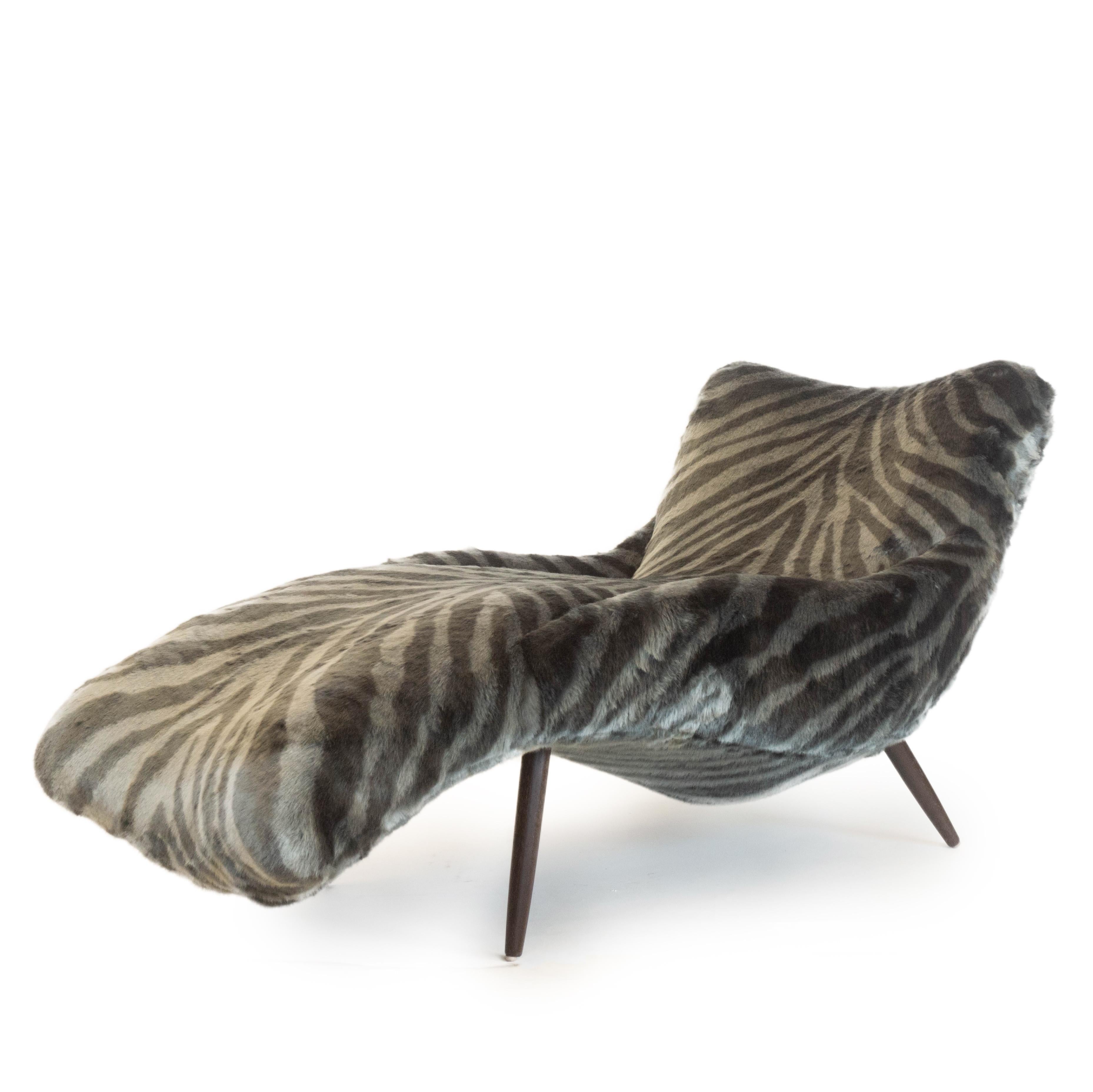 A lounge chair hand built by us in Norwalk, Connecticut upholstered in a soft faux tiger fur. This piece features a super comfortable sloping design for ultimate relaxation. This lounge chair also features exposed tapered legs made out of walnut.