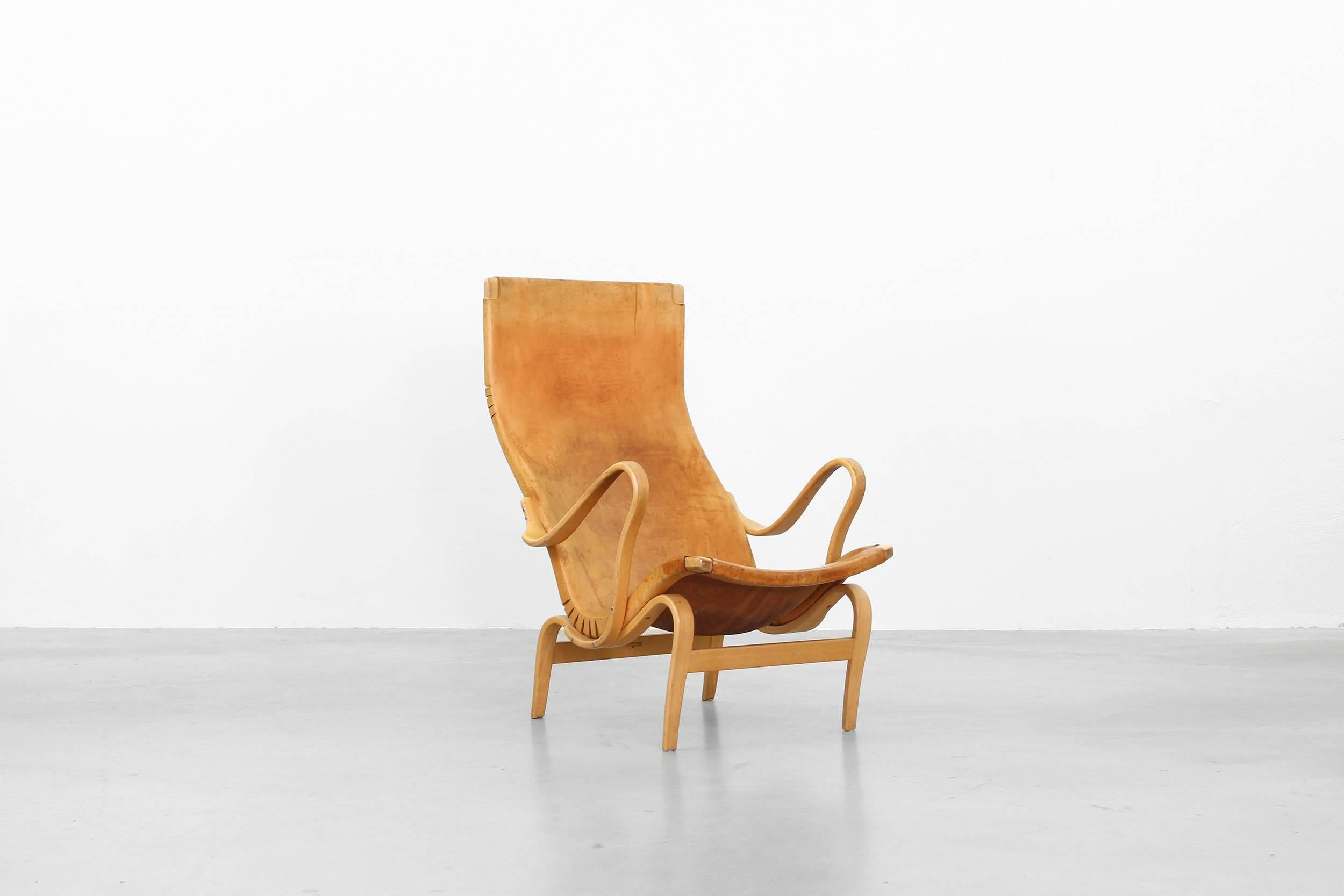 Very beautiful lounge chair designed by Bruno Mathsson for Karl Mathsson in the 1950ies. The chair is in a great condition and it comes with a patinated brown-cognac leather. Stamped serial number: 1067