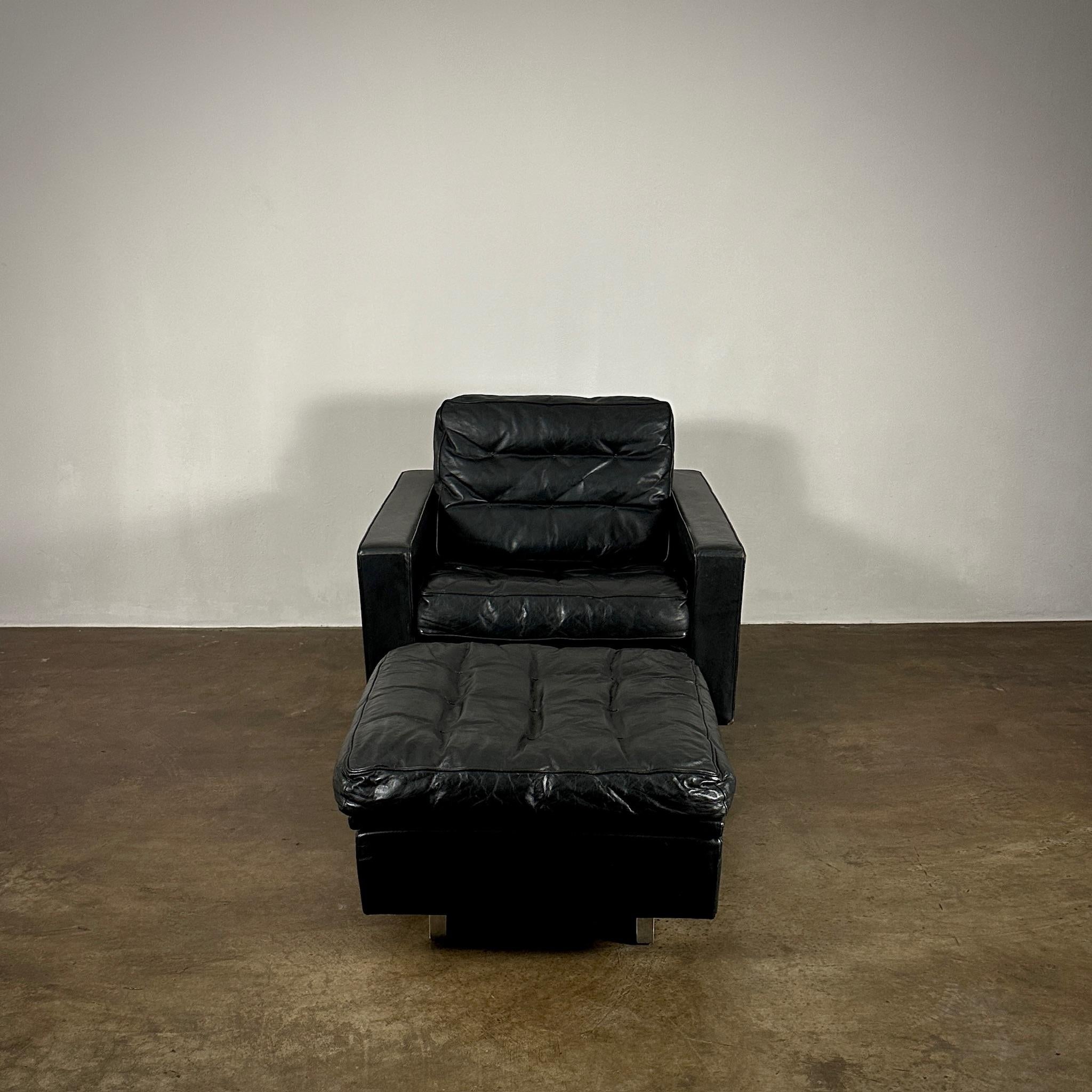 This De Sede lounge chair and ottoman set, model S802SC, crafted in Switzerland around 1960, embodies luxurious comfort with a sleek modern design. The pieces are upholstered in rich black leather with a slightly tufted finish that adds texture and