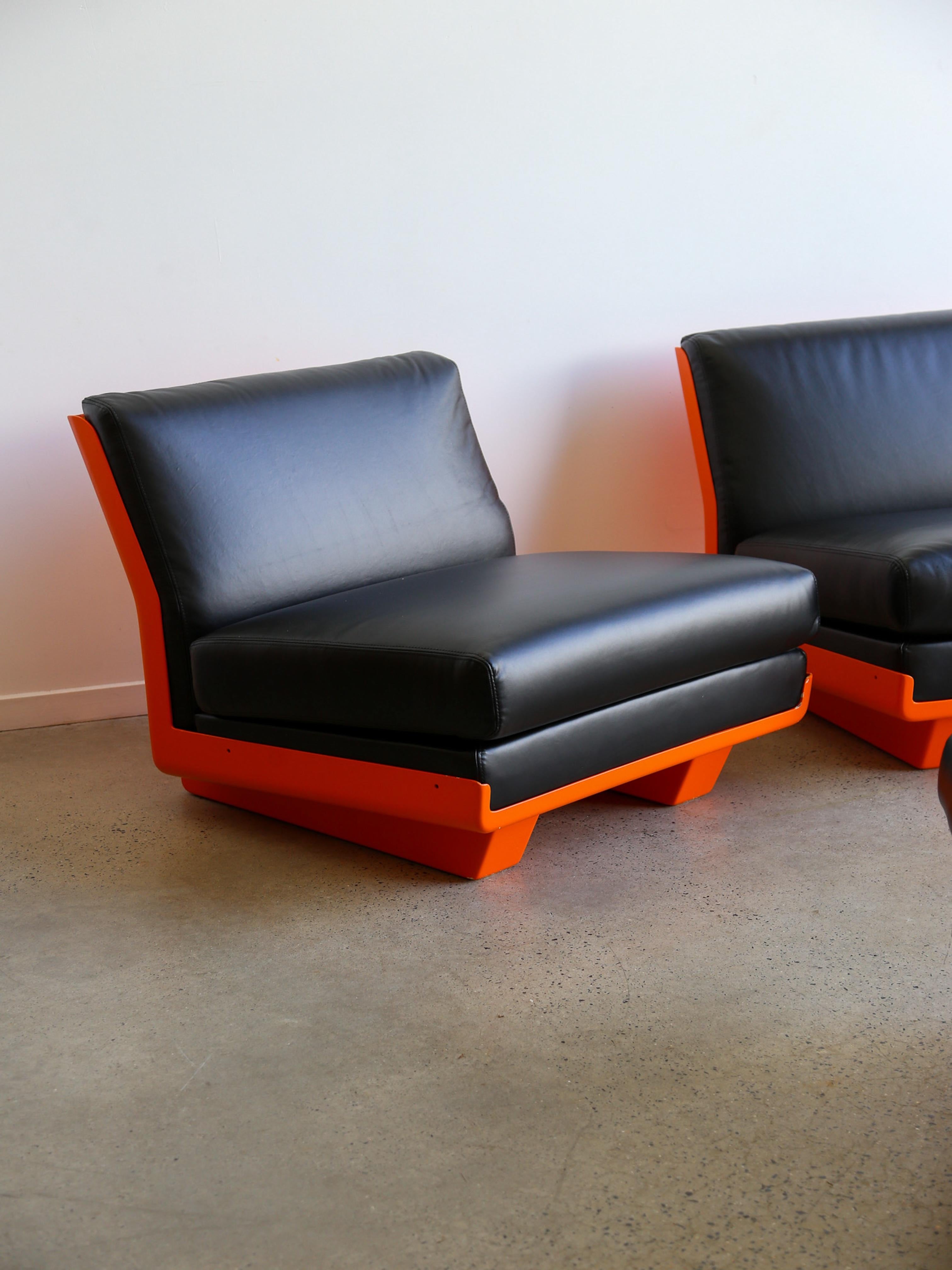 Eleva tu espacio con este atrevido y elegante conjunto de tumbonas, perfecto para interiores contemporáneos o despachos modernos. Con una vibrante base naranja hecha de resina y lujosos cojines de cuero negro, este conjunto está diseñado para