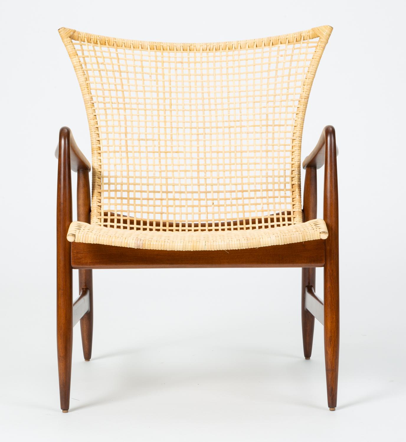 A 1958 design by Ib Kofod-Larsen for Selig, this refined lounge chair has a slight wingback design and delicately curved details. Petal shaped armrests swoop upwards into a rounded armrest with finely shaped joinery. Set into the walnut-stained