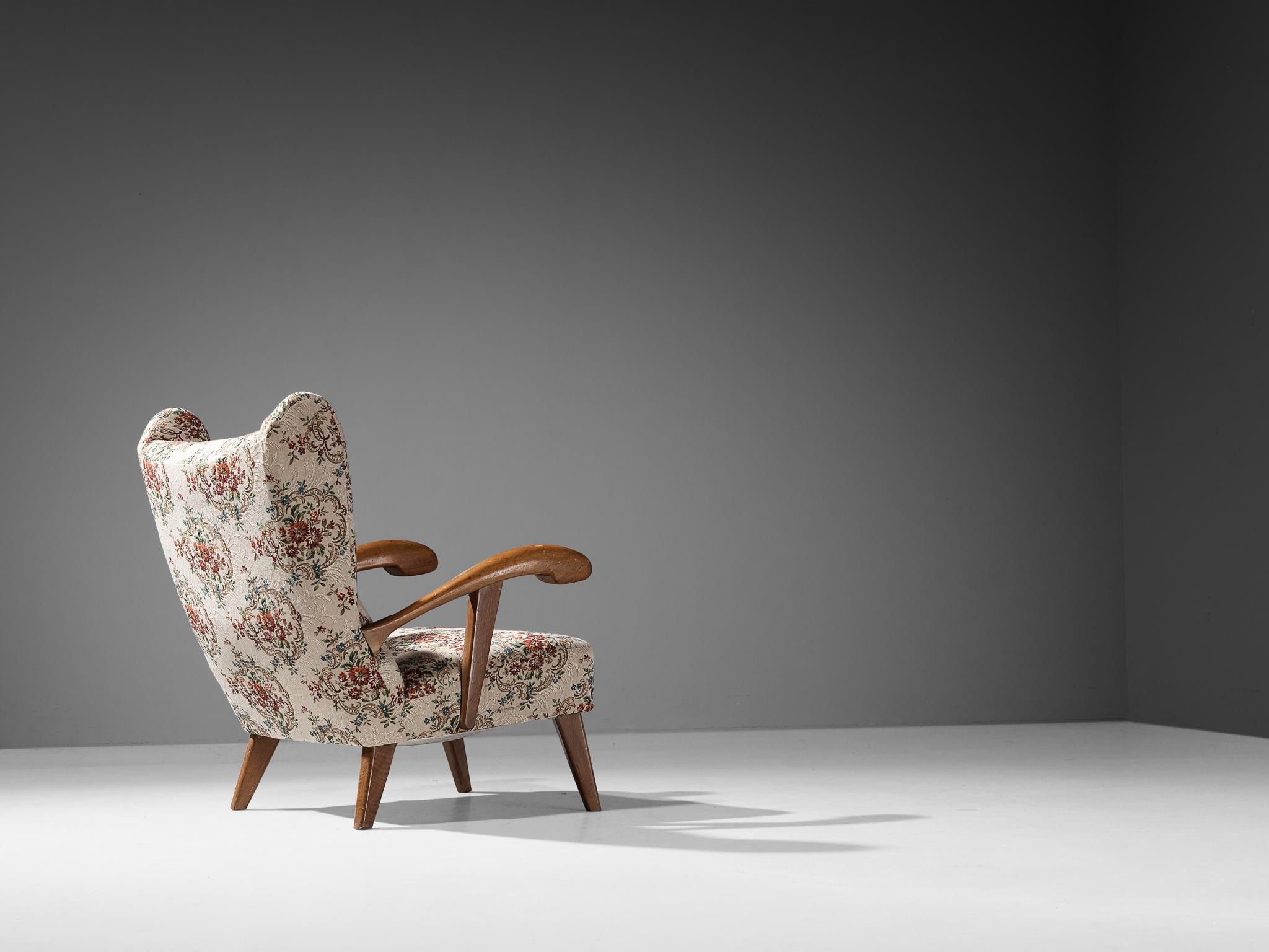 Lounge chair, stained beech, fabric, Czech Republic, 1950s. 

This beautifully designed lounge chair holds a striking construction by means of the sculpted elements discernible in the wooden frame and back. The armrests are characterized by