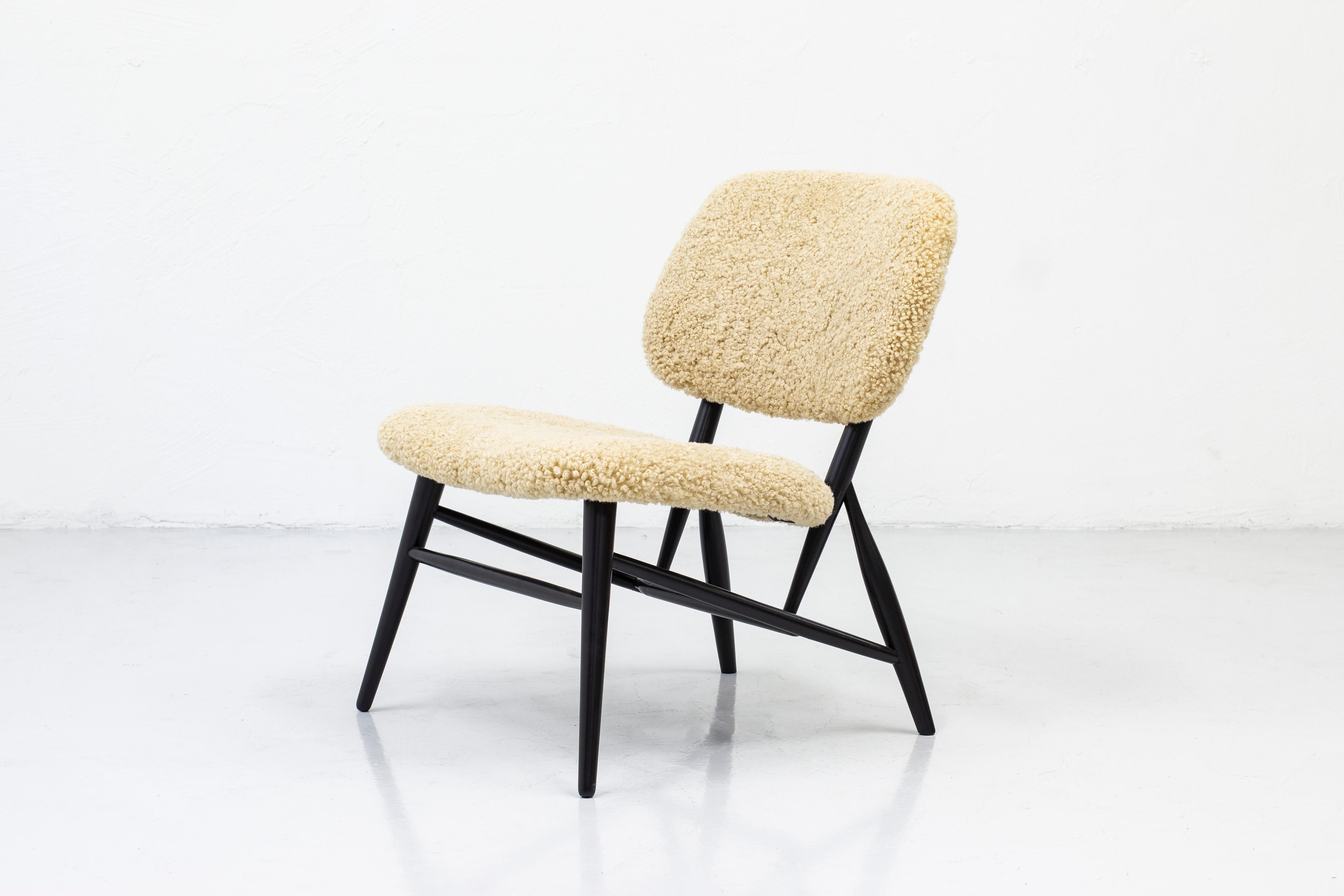 Lounge chair by Diö Slöjd & Möbler. In the manner of Alf Svenssons Te-Ve lounge chair Produced in Sweden during the 1950s. Solid beech frame with black paint and new sheep skin upholstery in beige. Excellent vintage condition with few signs of