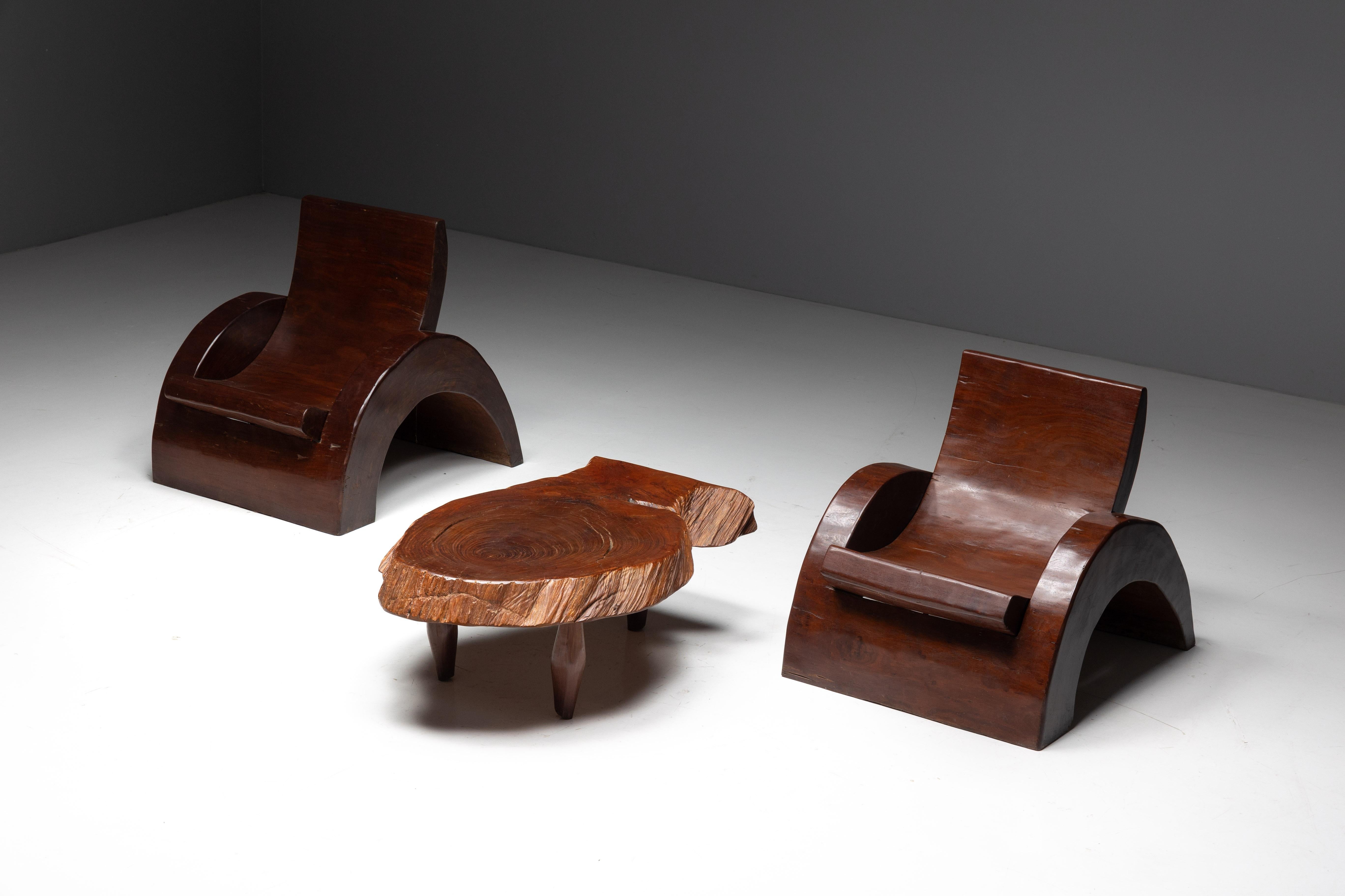 This rare and striking set, crafted by Brazilian designer José Zanine Caldas in the 1970s, features two sculptural lounge chairs and a stunning coffee table made from richly grained tropical wood. The lounge chairs are defined by their curvilinear,