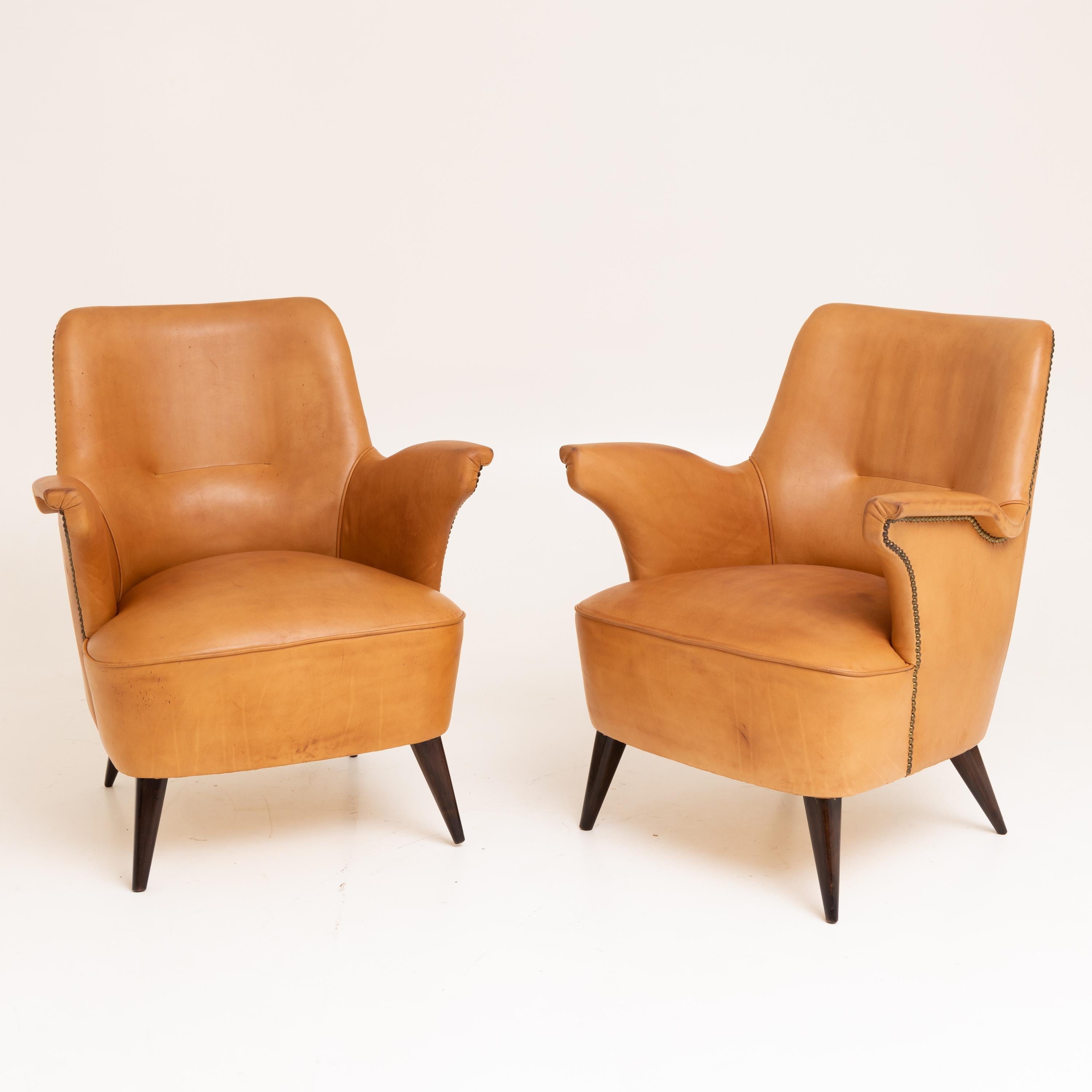 Two armchairs, attributed to Giovanni Zoncada (1898-1988), with brown imitation leather upholstery on conical wooden feet.