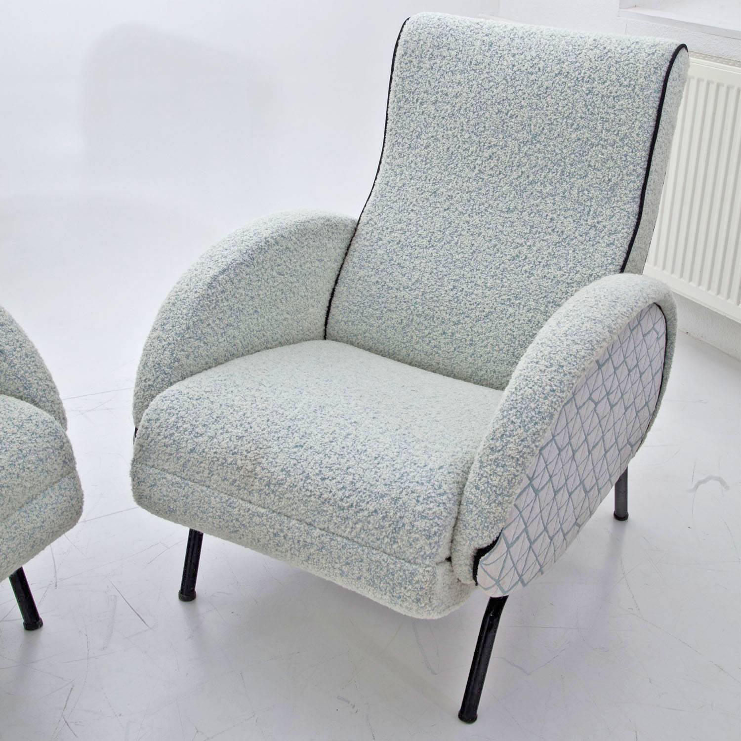 Pair of reclining lounge chairs on black iron feet with oval armrests. While leaning back, the footrests extend out. The armchairs were reupholstered with a high quality fabric in white and turquoise. Labelled on the rear iron bar.