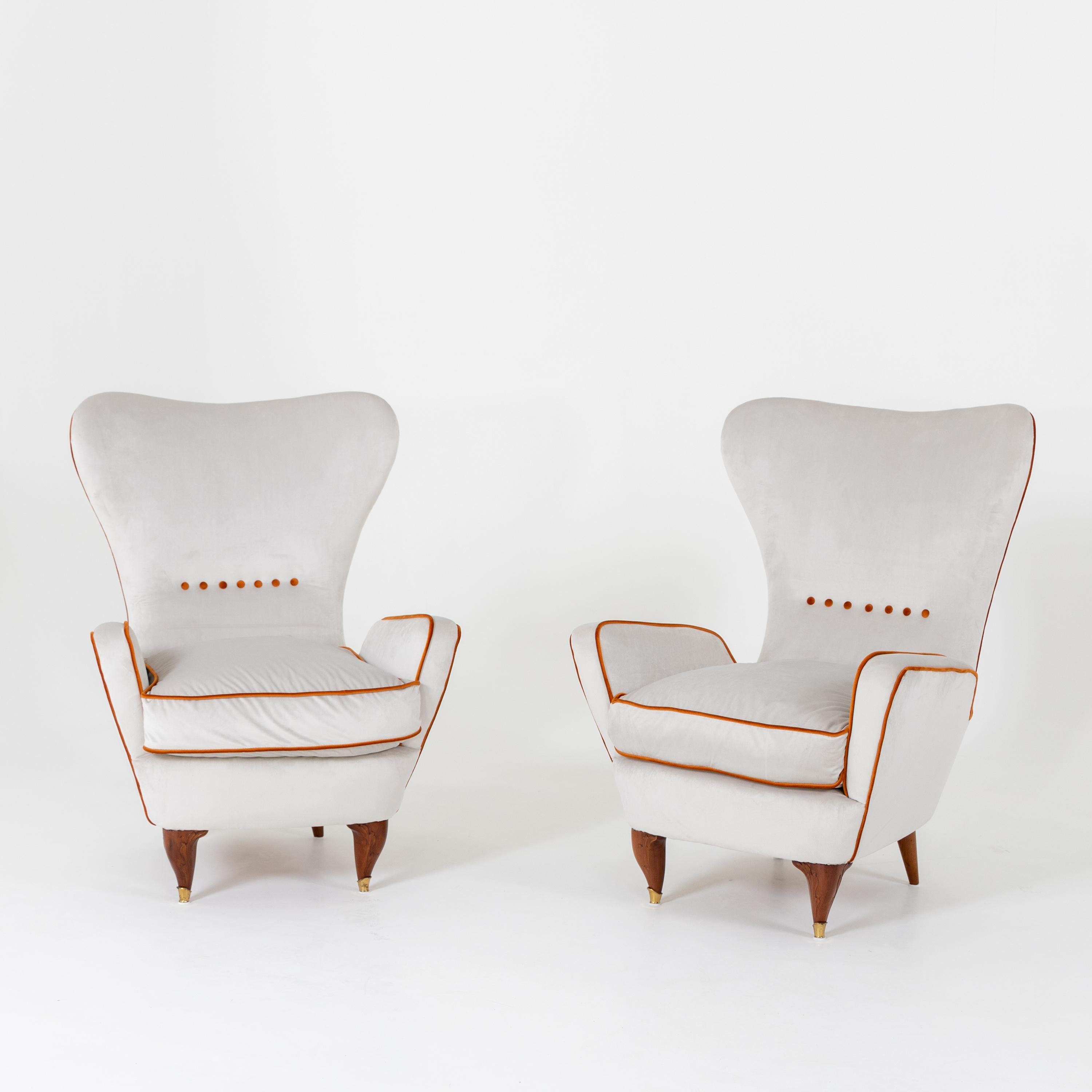 Pair of lounge armchairs with wide trapezoidal backs and thickly upholstered seat and armrests, designed by Paolo Buffa in the 1950s. The armrests leave a small gap to the backrest, which gives the armchairs their unusual profile view. The armchairs