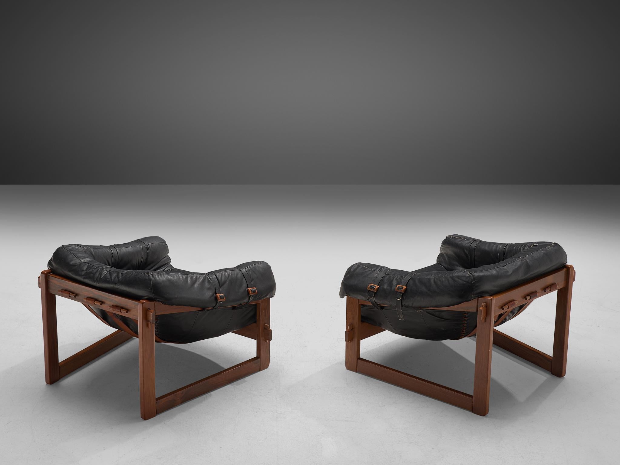Percival Lafer, pair of lounge chairs, leather and wood, Brazil, 1960s

Bulky and grand lounge chairs by Brazilian designer Percival Lafer. This set features a solid dark wooden base with leather straps spanned between the slats. The tufted leather