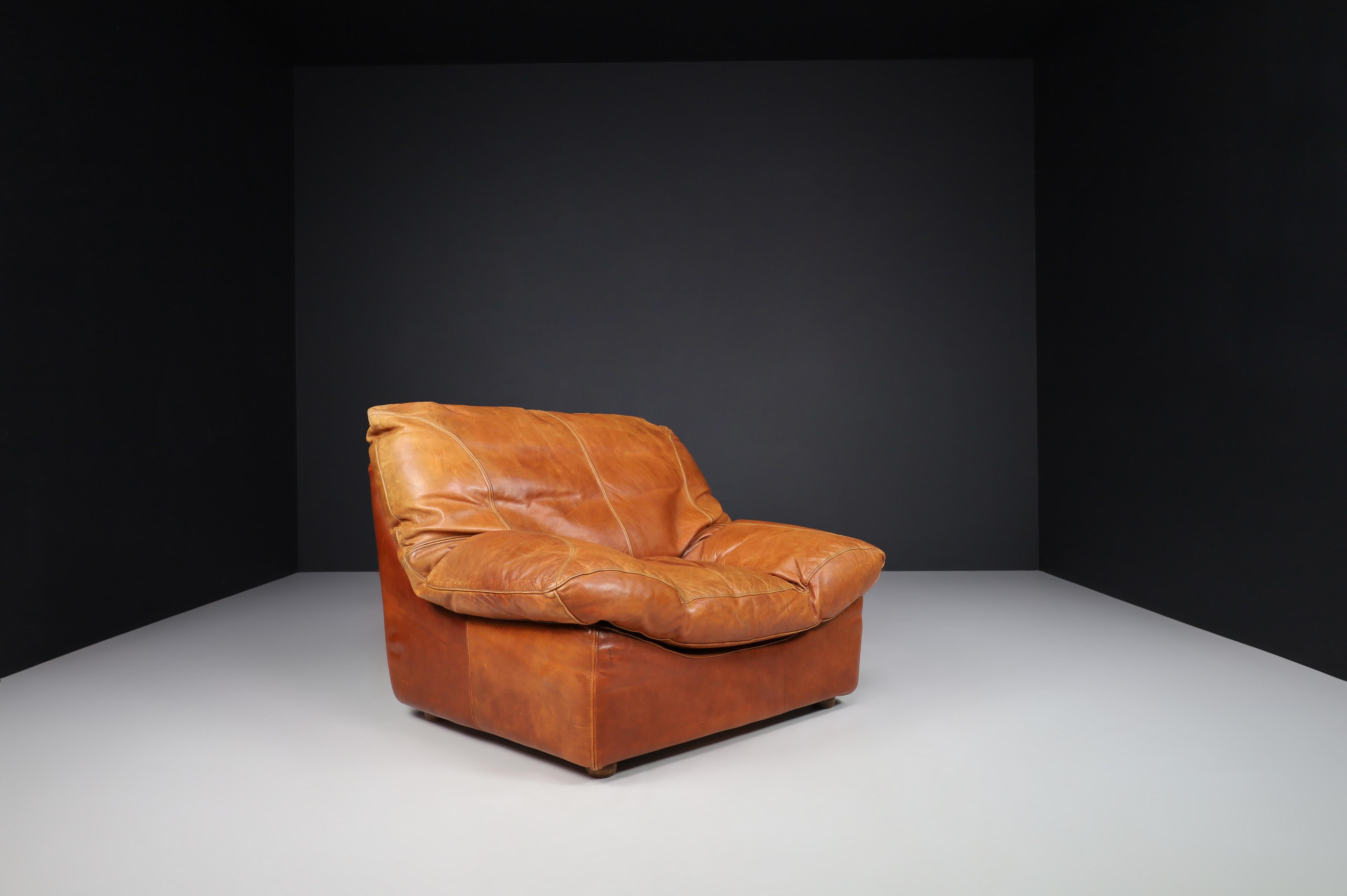 Lounge chairs in Patinated Cognac leather, France 1970.

Oversized, large, modern lounge armchairs that feature straight lines and shapes invite you to take a seat and relax—designed in France in the 1970s. Well-proportioned brown patinated cognac