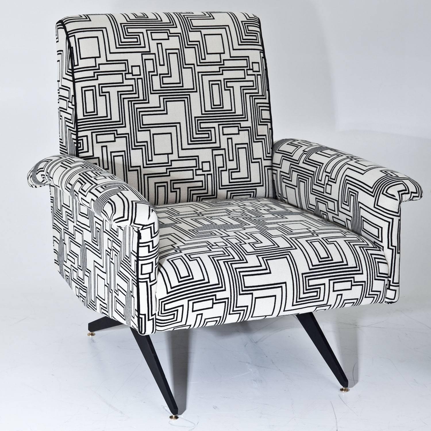 Pair of lounge chairs, standing on black metal legs with brass feet and thickly cushioned seats and backrests. The armrests are slightly curved. The armchairs were reupholstered with a high quality black-and-white patterned fabric by designer Eley