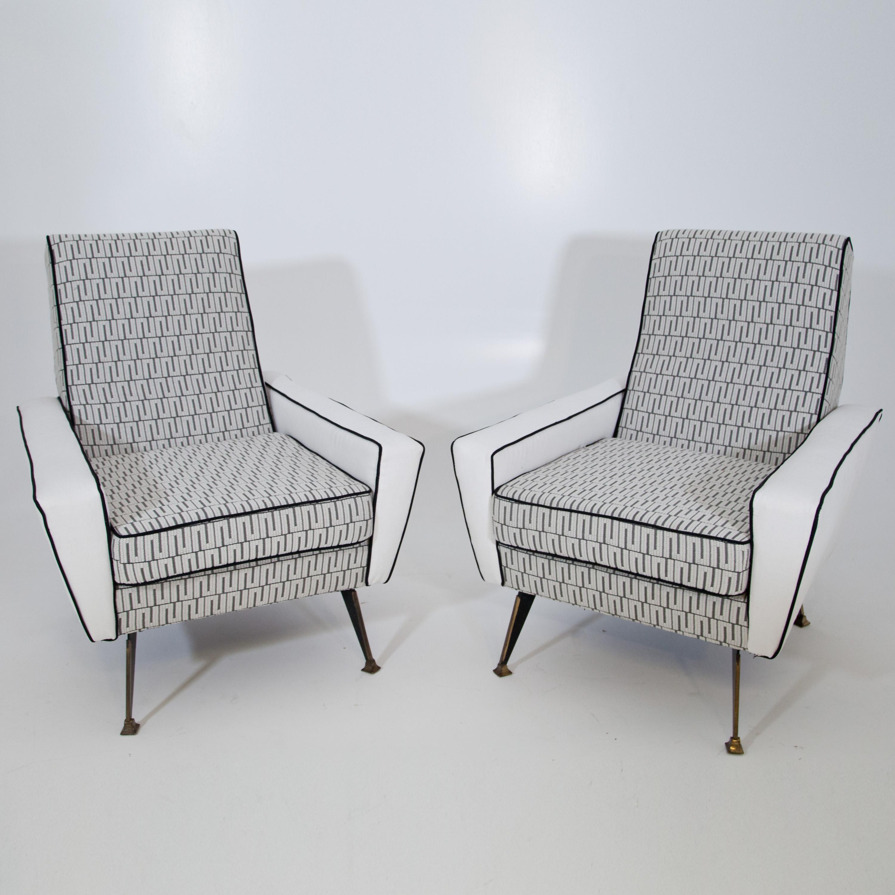 Pair of midcentury lounge chairs on metal legs and wide upholstered seat. They are newly upholstered with a high-quality fabric in cream and grey with Meander design and black piping.