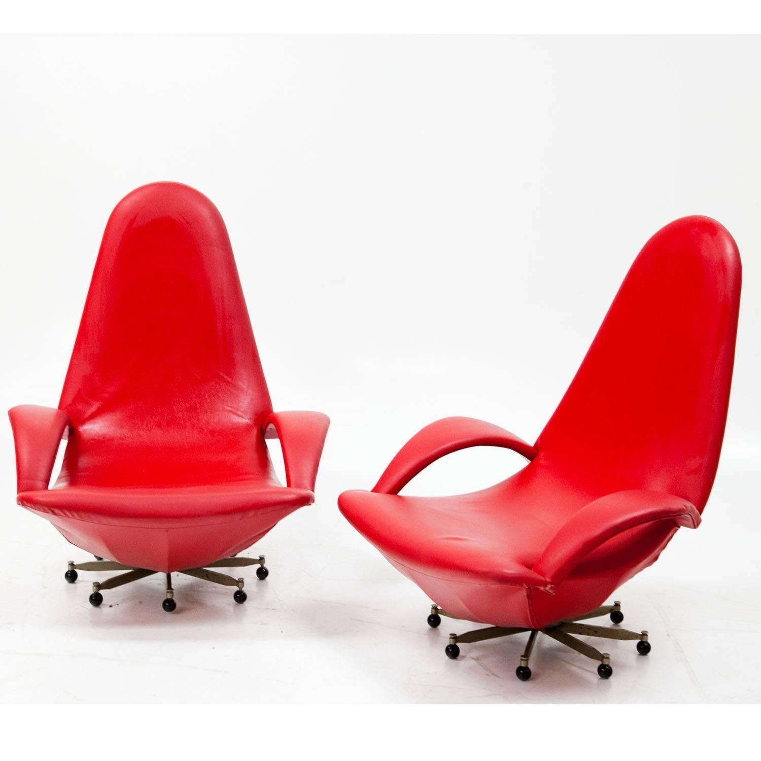 Pair of red lounge chairs, upholstered with a red faux leather. The chairs show organic forms, tall backrests and curved armrest. They stand on an eight-armed foot with black wheels.