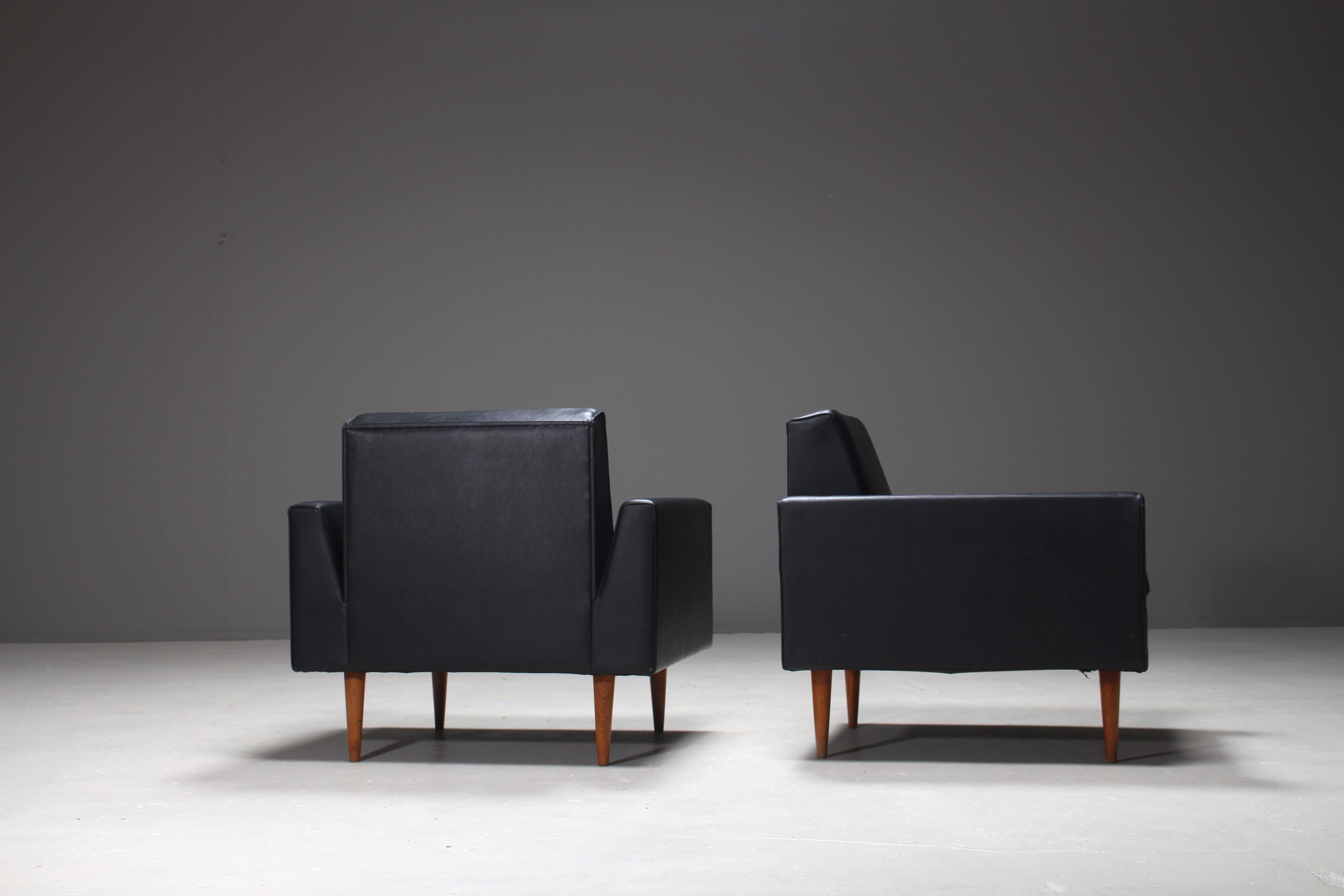 Pair of club chairs designed by Theo Ruth for Artifort in 1955. The chairs are upholstered in the original Artifort black leatherette. This is the early edition of the model 410 for Artifort, with the distinctive cone-shaped oak legs. This first