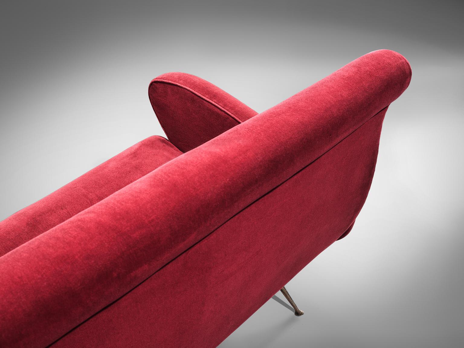 Lounge set, red velvet, brass, Italy, 1950s. 

This set is an iconic example of Italian design from the fifties. Organic and sculptural, the two seat sofa and two matching lounge chairs with ottomans is anything but minimalistic. Equipped with the