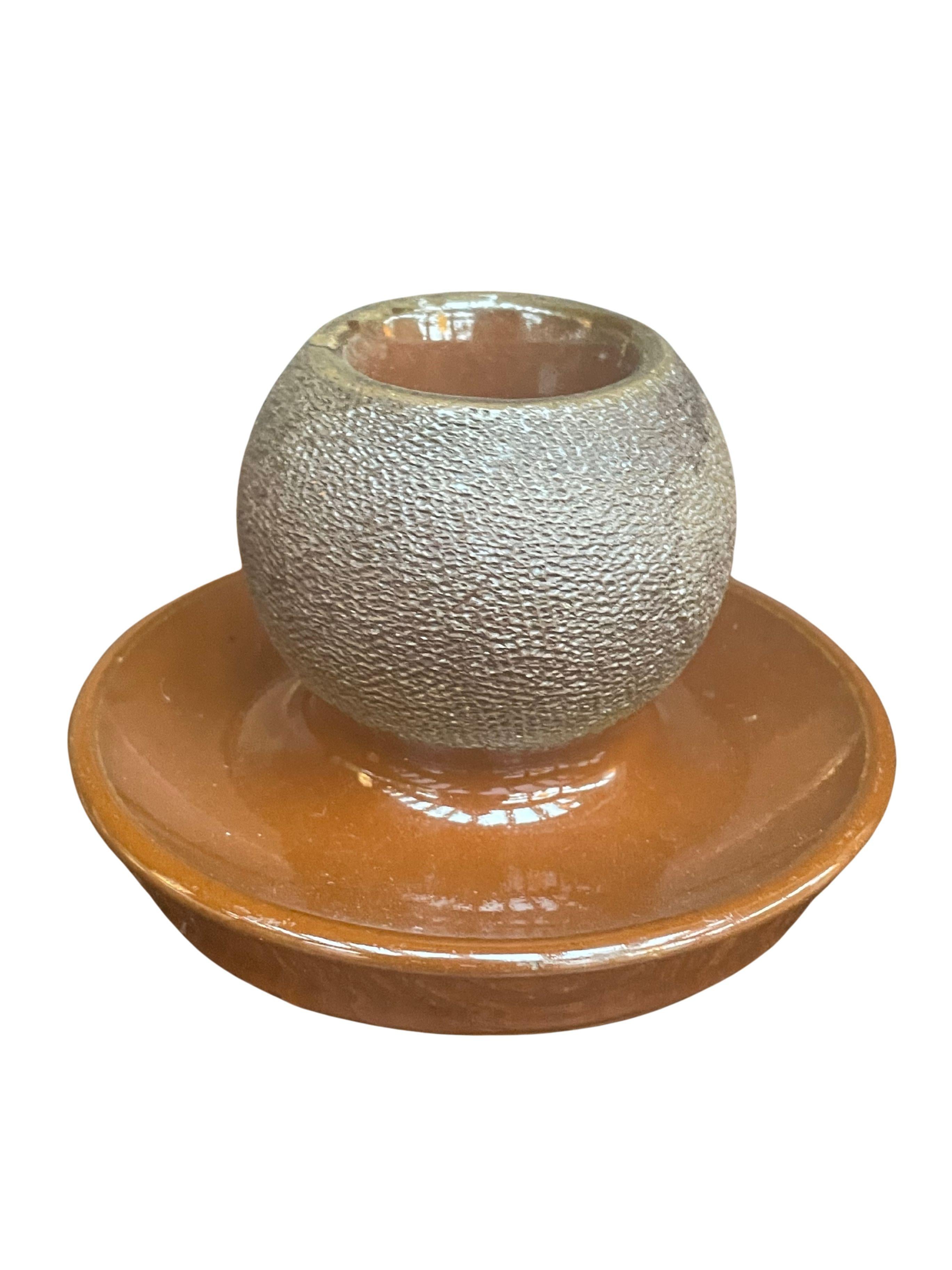 A charming early–mid 20th century Lovatt Langley ceramic match striker, featuring the pottery’s signature warm brown glaze and finely textured unglazed striker surface. The spherical striker sits atop a wide glazed dish designed to catch spent