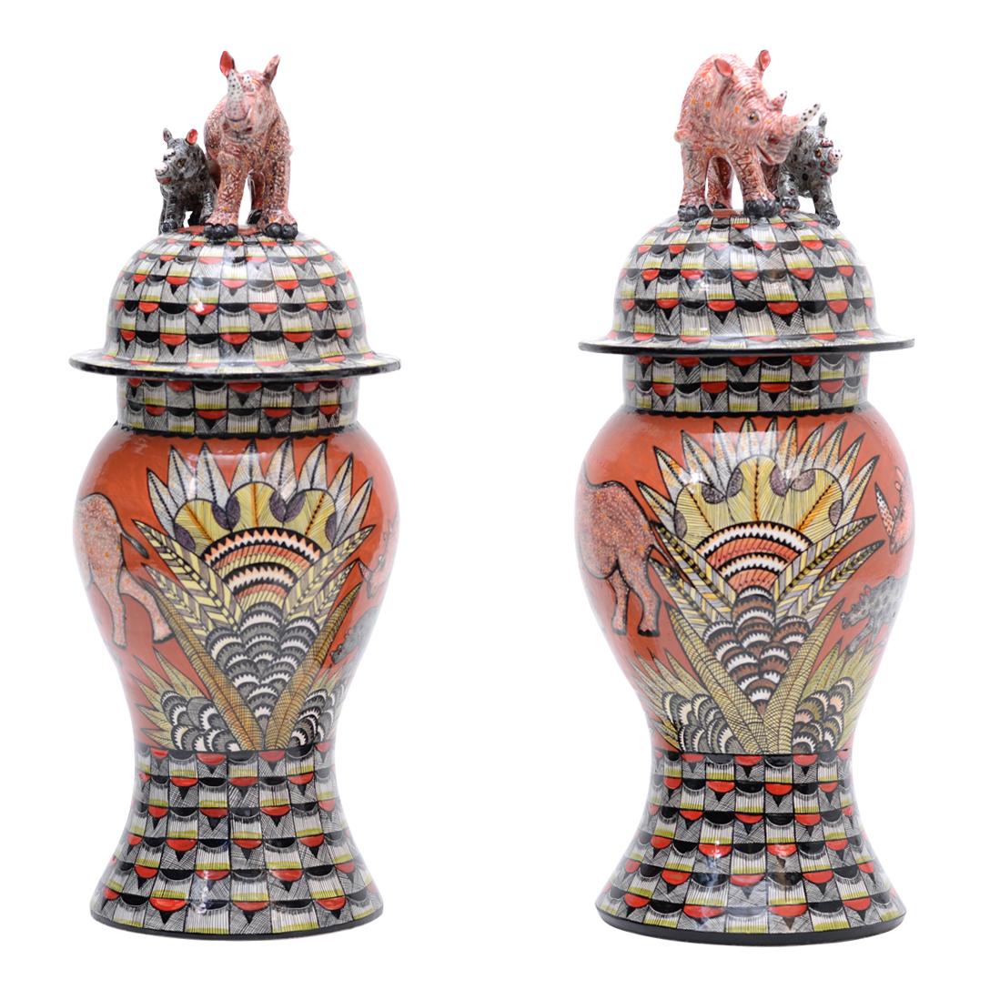 Experience the essence of African wilderness with the Rhino Urn by Love Art Ceramic. Hand-sculpted by Sabelo Ntshalintshali and painted by Winnie Nene in South Africa, this unique pair of urns depicts a mother rhino and her baby, symbolizing