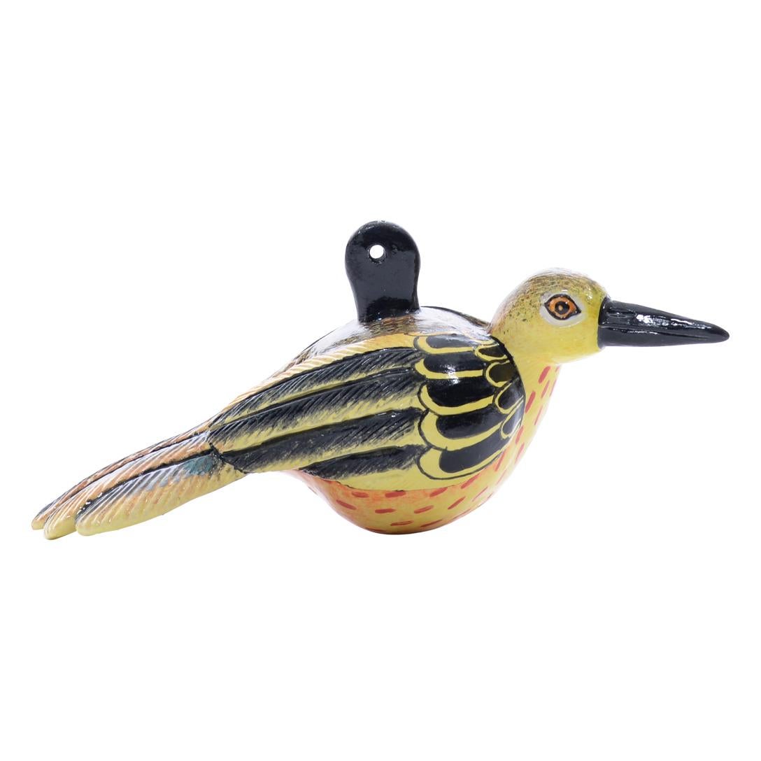 The ceramic Bird ornament by Love Art Ceramic in South Africa, measuring 2 inches high, 5 inches long, and 2 inches wide, is hand-painted by Nozipho Ntshalintshali and hand-sculpted by Sondelani Ntshalintshali. It depicts a charming bird with yellow