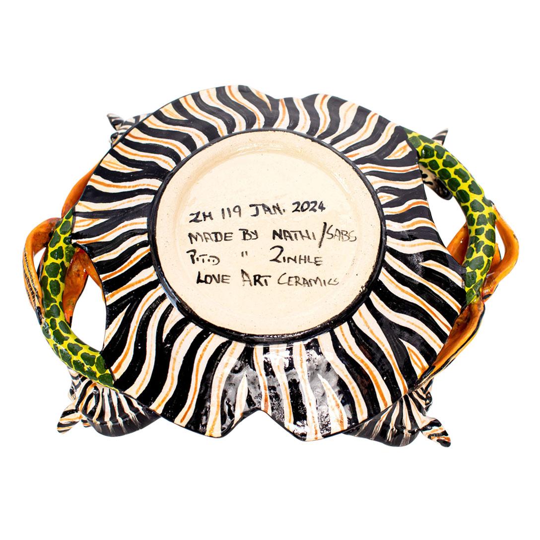 Introducing the Zebra Coin Dish by Love Art Ceramic, a beautiful piece handcrafted in South Africa. Measuring 2 inches high, 8 inches long, and 6 inches wide, it features two sculpted zebra heads grazing on palm tree foliage. Hand-painted by Zinhle