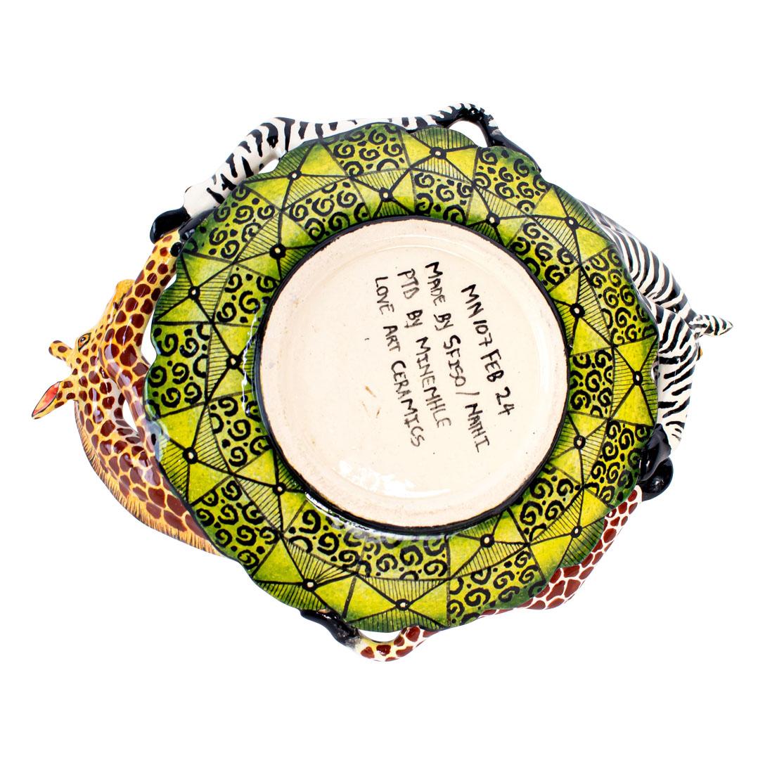 This handcrafted ceramic Giraffe & Zebra coin dish is a tribute to the rich biodiversity of Africa. Hand-painted by Minenhle Nene and hand-sculpted by Nathi at Love Art Ceramic studio, it measures 2 inches high, 8 inches long, and 6 inches wide. The