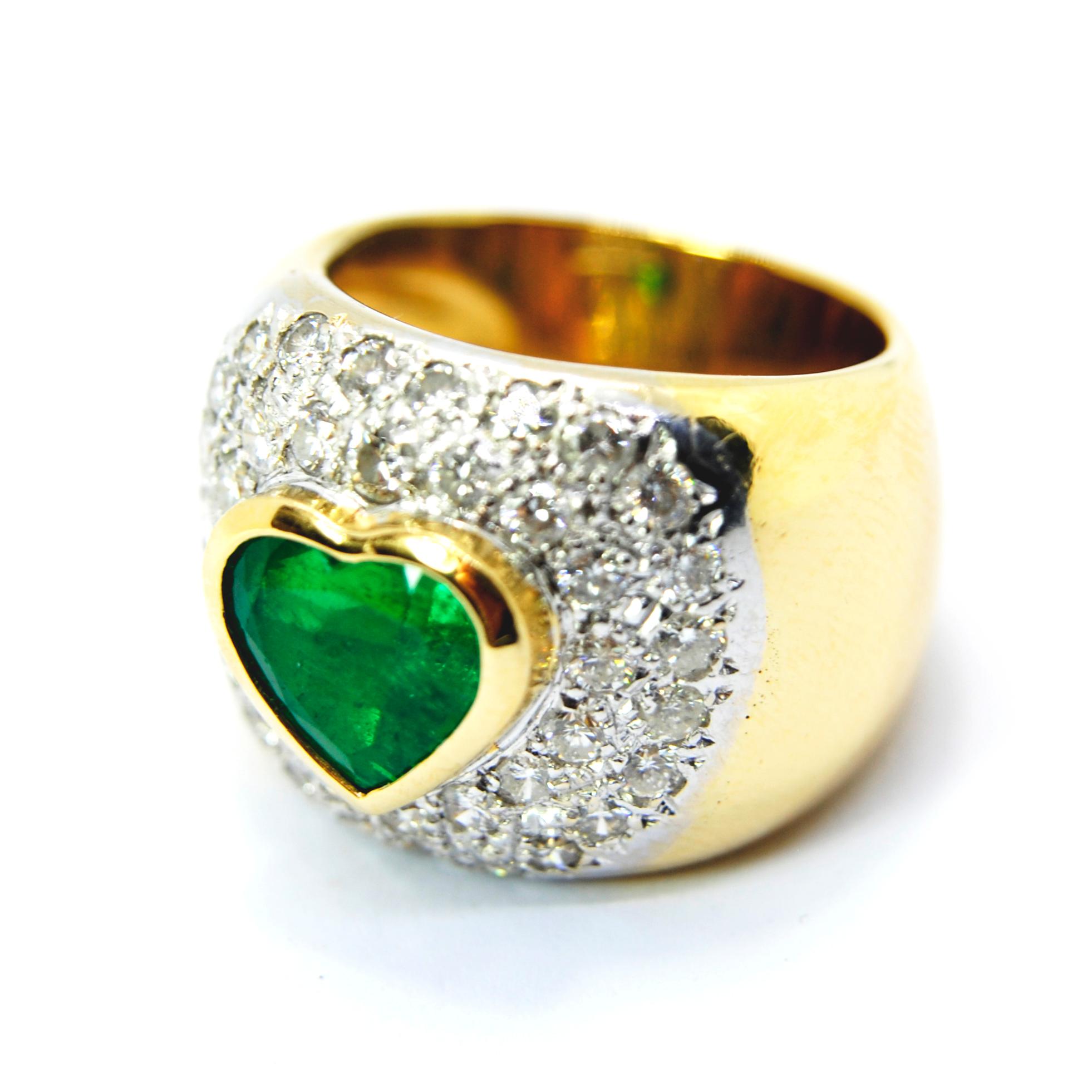 This timeless heart shaped emerald and diamond ring is crafted in a combination of solid platinum and yellow gold. Composed of a heart shaped frame pave-set with round-cut diamonds weighing approx. 1.20 carats, graded H-I color, and VS clarity.