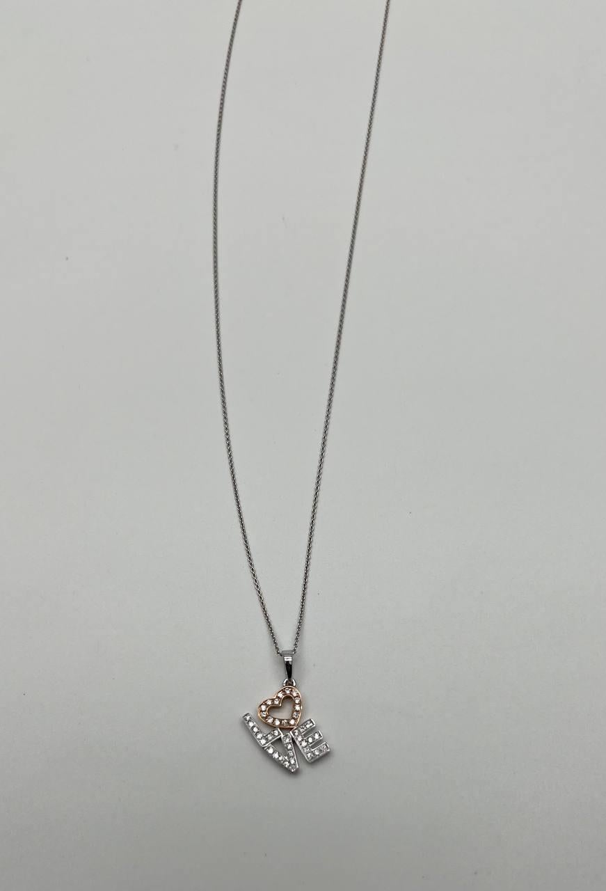 Pendant necklace featuring a heart-shaped motif with a rose gold finish, encrusted with round brilliant-cut stones. The pendant spells 