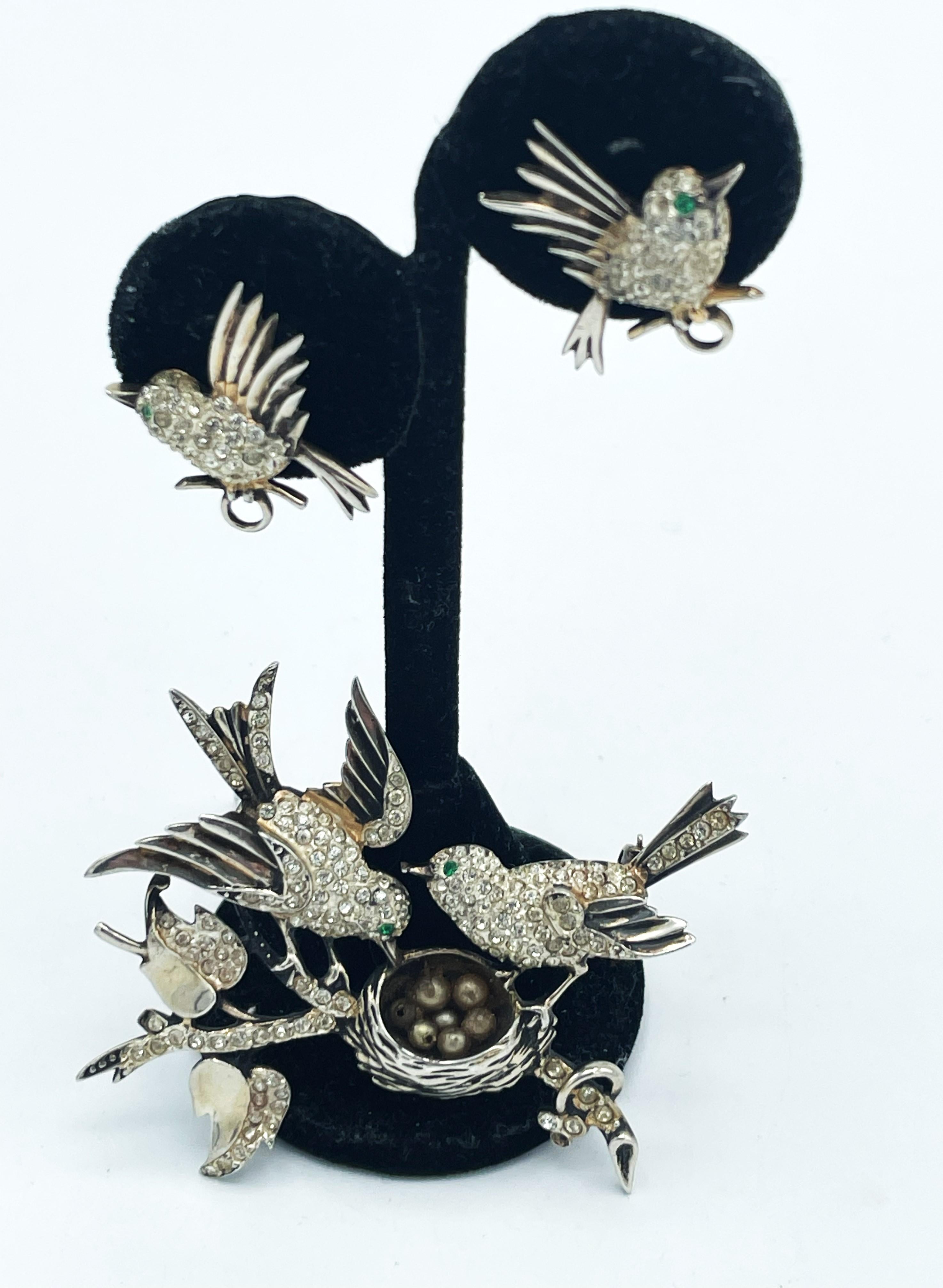 Brooch of a pair of birds sitting on a branch with a nest, matching 2 small bird ear clips that are already fledged.
Signed 'house of Schrager Creation NY' Sterling 1940. The birds, leaves and branches filled with the smallest