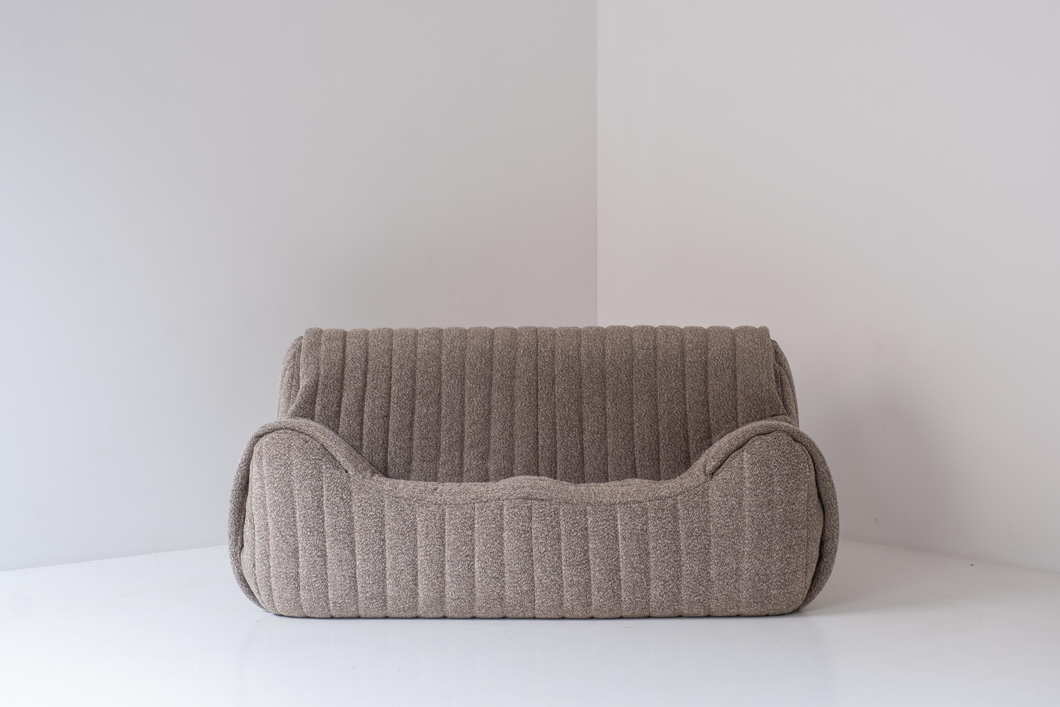 Lovely 2-seater sofa sourced in France, dating from the 1960s. The inside of the sofa consists entirely of polyether and is professionally re-upholstered in a ribbed wool fabric. It seems as if the fabric is folded very subtly around the armrests,