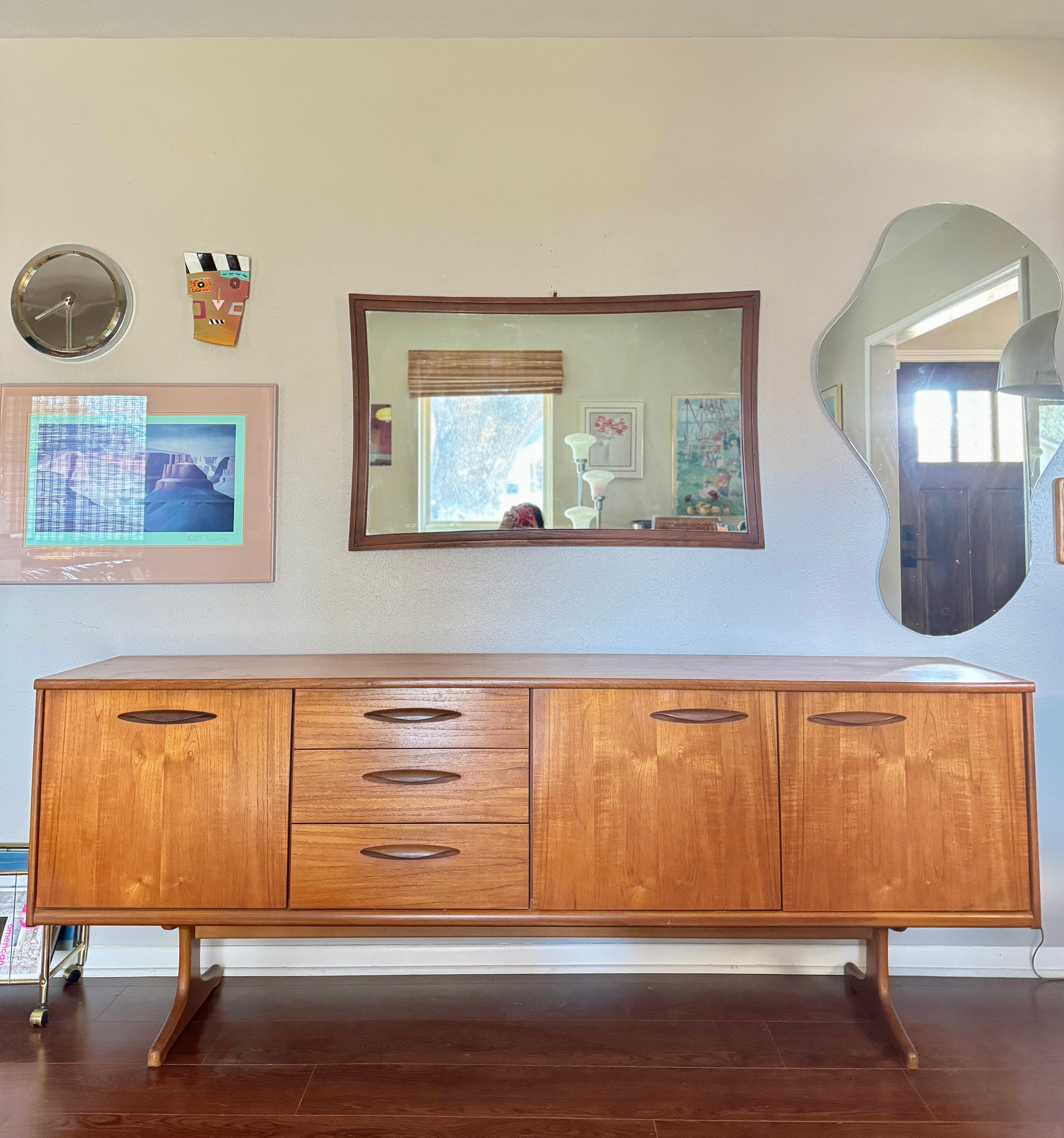 Lovely 84” sideboard designed by Frank Guille and manufactured by Austinsuite, circa 1960s. This large sideboard features stylish handles, solid teak sleigh legs, and is made from a smooth light teak veneer with darker Afromosia solid wood handles.