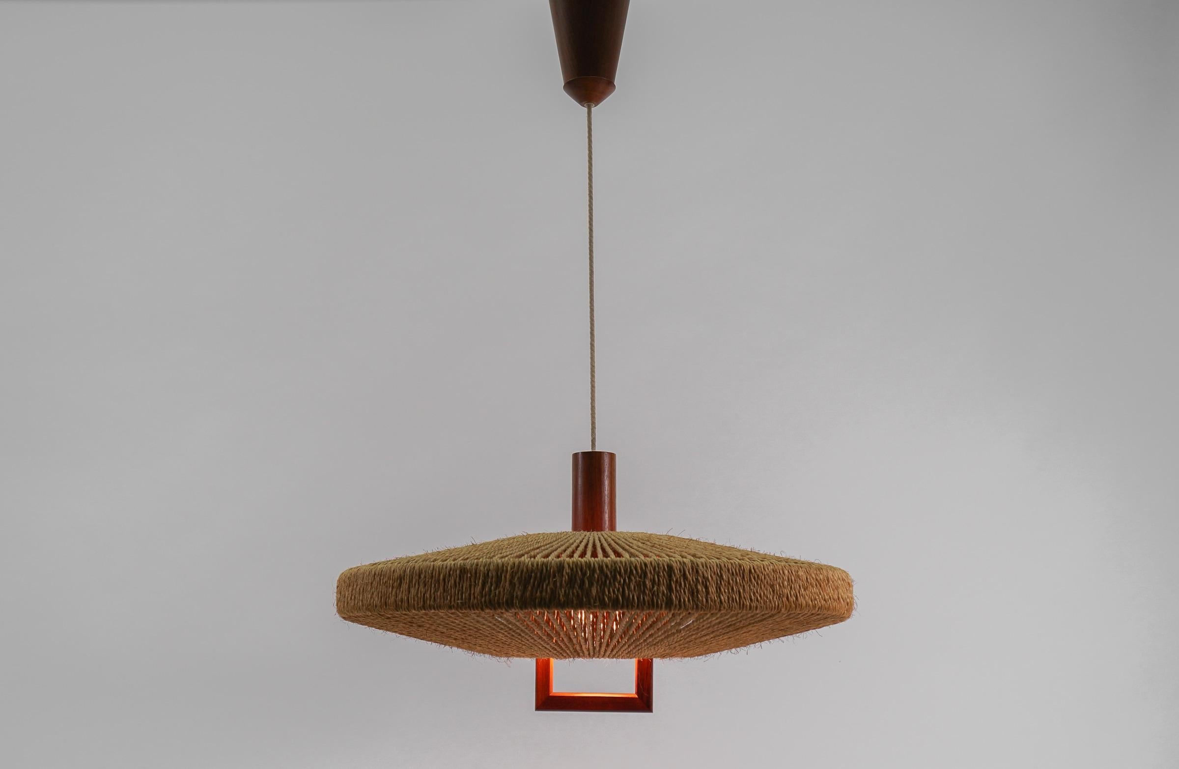 Large shapely teak lamp with jute cord weave.

Adjustable from 60cm to 160cm. 

The lamp is executed with one E27 Edison screw fit bulb. It is wired and in working condition. It runs both on 110 / 230 volt.

The small recess on the baldachin is for
