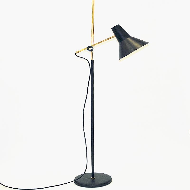 Black and classic Norwegian metal and brass floor lamp by Høvik Verk 1970s. Black metal stom divided with brass on the upper part included the lamp shade pole. The black shade is adjustable up an down its pole to make the lamp higher or lower after
