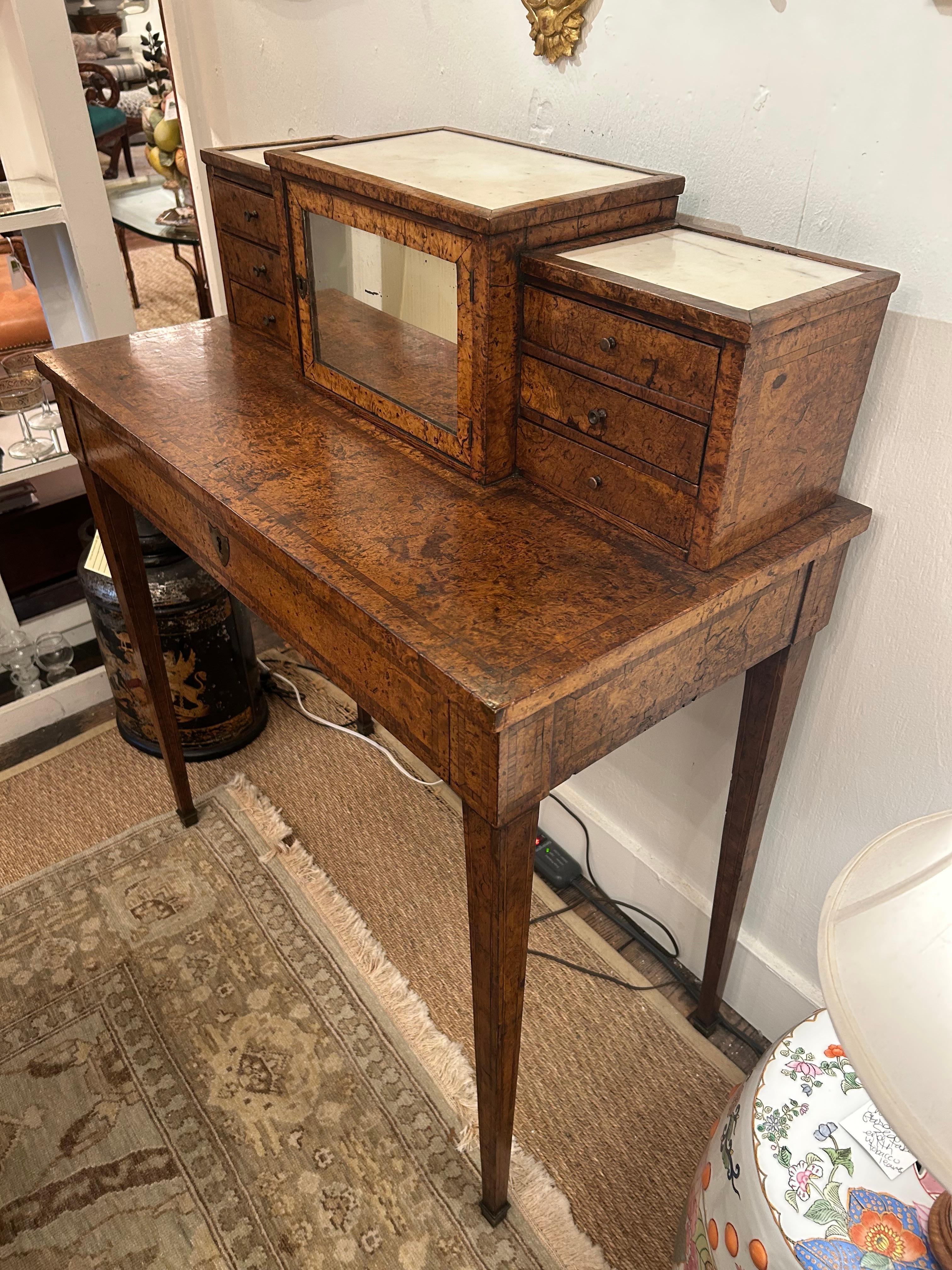 Lovely antique Burl dressing table having little drawers and mirrored door with storage inside.  Single drawer pulls out and has tooled leather sliding top.  Small surface for make up or jewelry.
To surface 31.5
Apron 27.5