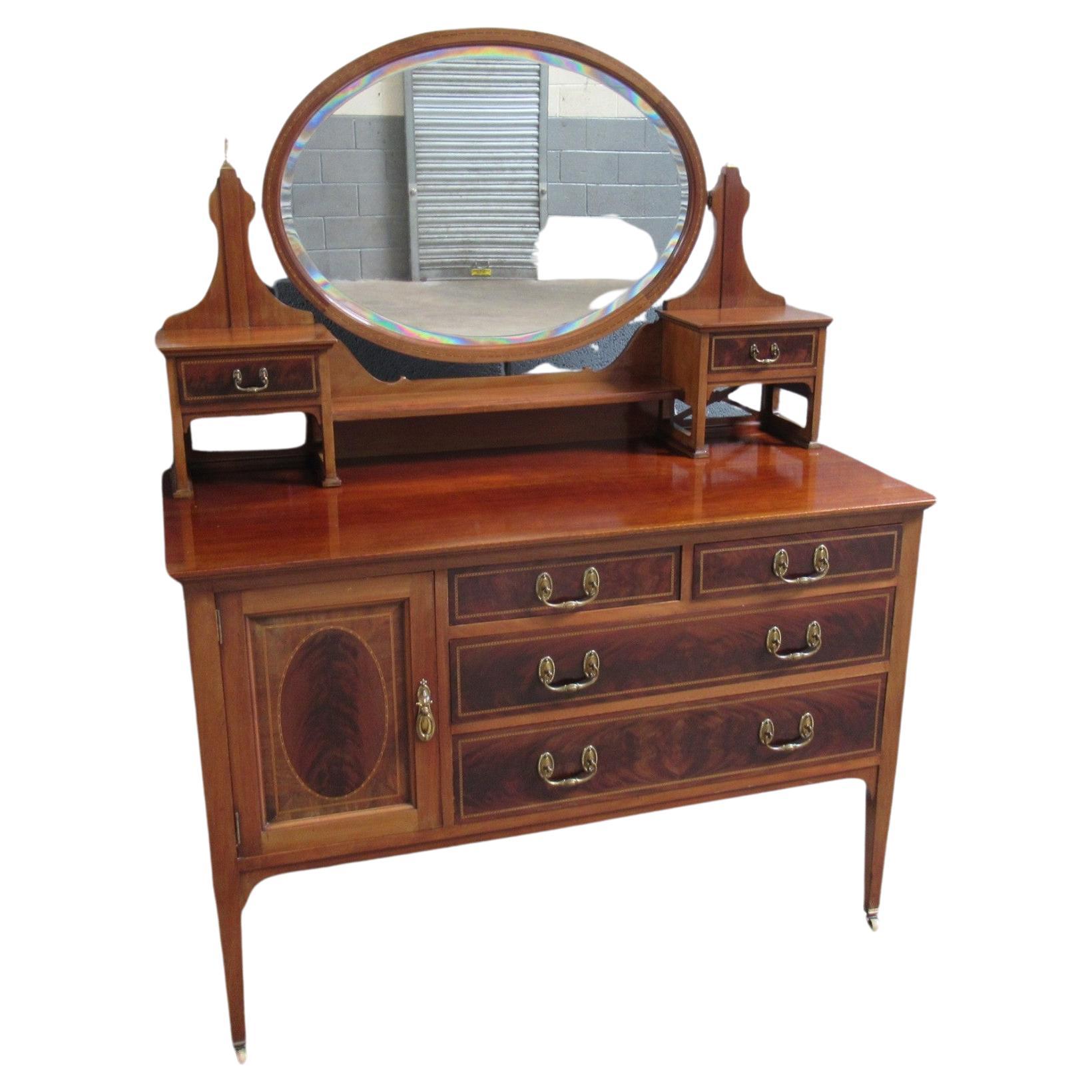 A Lovely Antique English Edwardian Inlaid Flame or Crotch Mahogany Ladies Dressing Table or Vanity with attached (and removable) original oval framed mirror.  This piece is made from superior materials including hand-dovetailed mahogany drawer