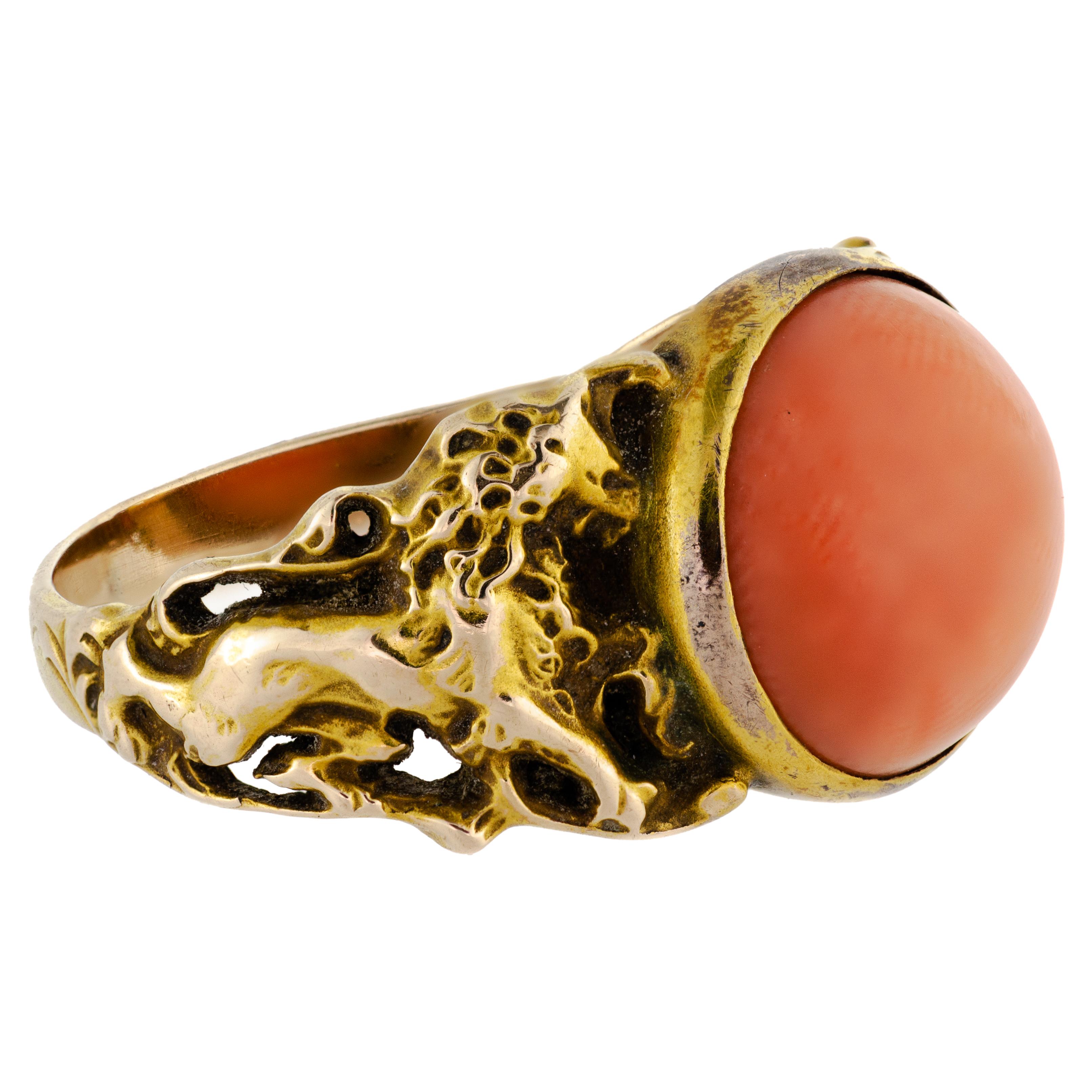 This stunning Art Nouveau ring dates back to the early 1900s and boasts an exquisite natural coral cabochon at its center. The cabochon is bezel set in a beautifully crafted floral openwork design mount of 14kt yellow gold. The intricate details of