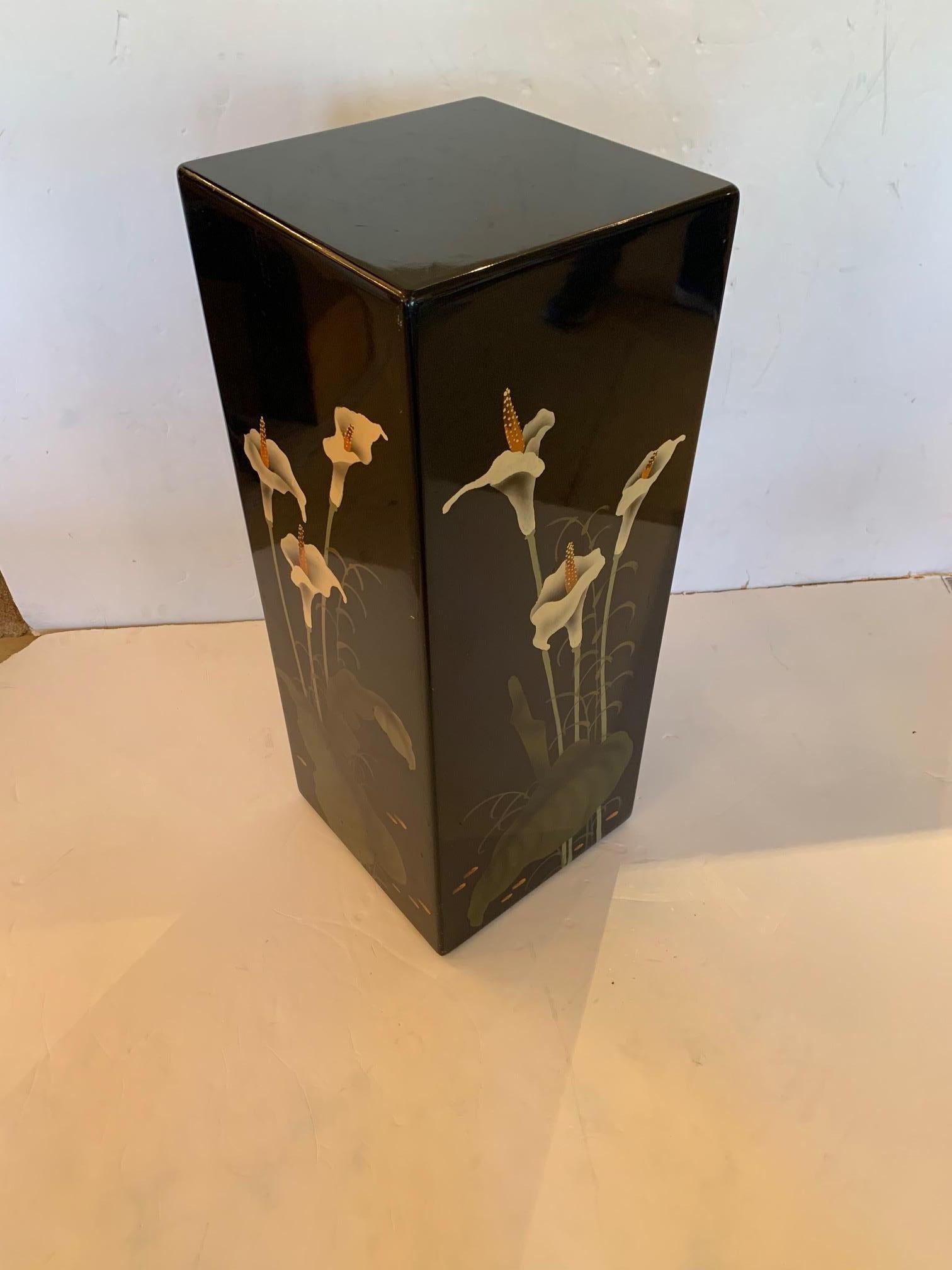 A beautiful stand or pedestal for displaying art or a plant that is like a piece of art itself having black lacquer background and striking painted decoration with calla lily flowers and leaves.