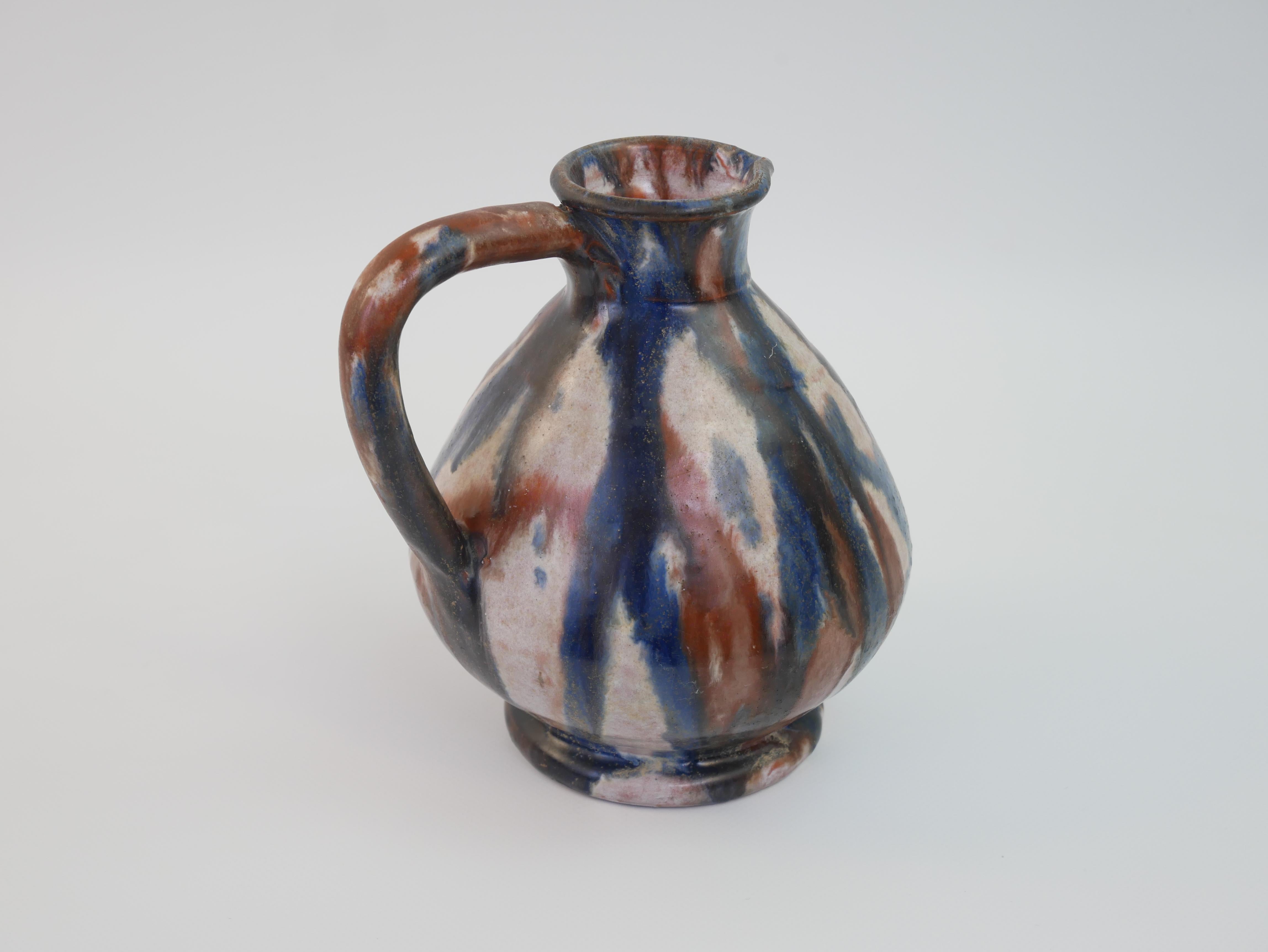 Questa brocca in ceramica della metà del XX secolo proveniente da Vallauris, in Francia, riflette l'estro artistico degli anni '50, quando Vallauris divenne un centro di innovazione ceramica. Conosciuta per i suoi ricchi disegni dipinti a mano, la