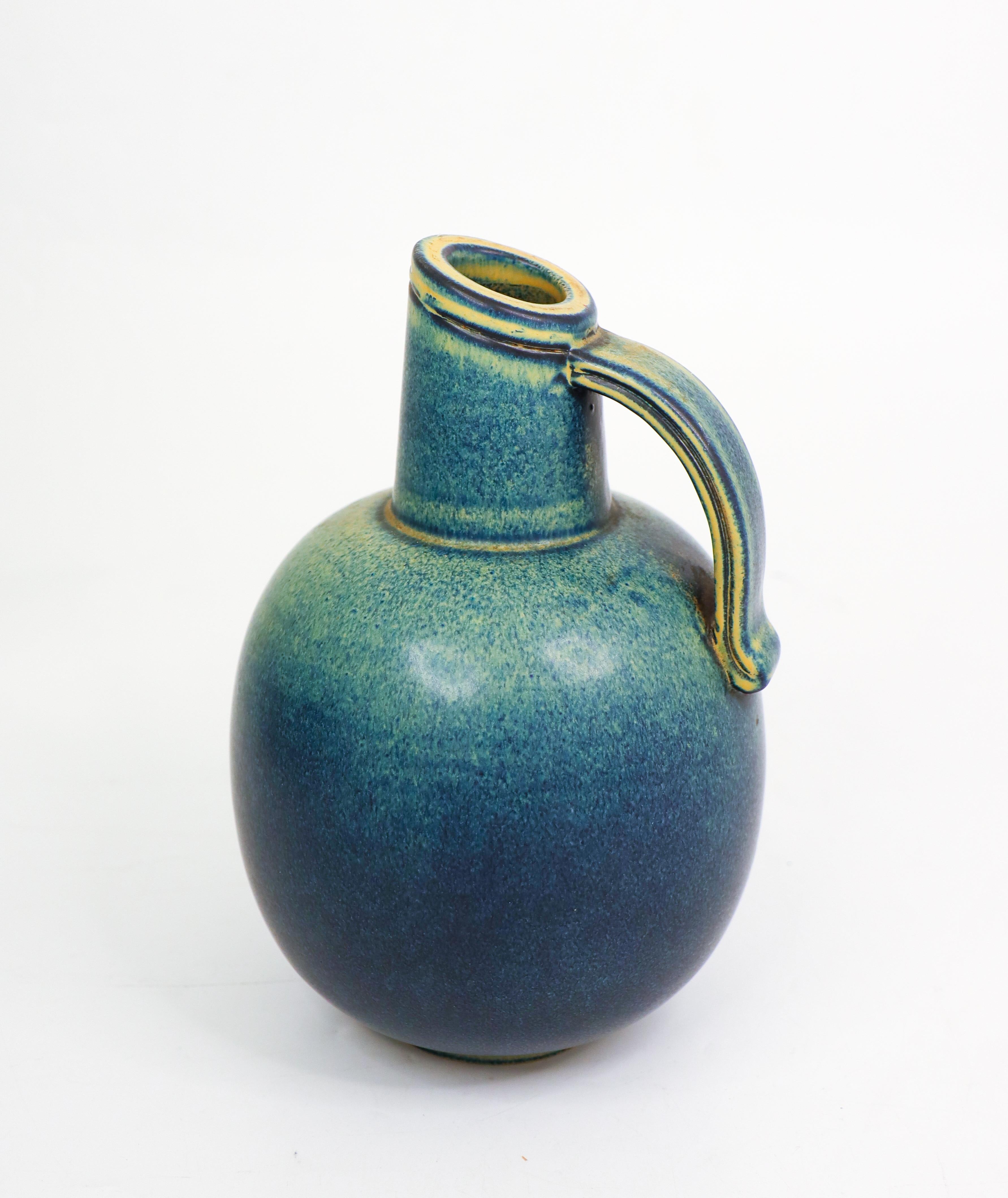 Un vase en céramique bleu et vert conçu par Gunnar Nylund chez Rörstrand. Il mesure 17,5 cm de haut et environ 17 cm de diamètre. Il est en excellent état. Le vase est marqué comme le montre la photo et il est marqué comme étant de 1ère qualité.