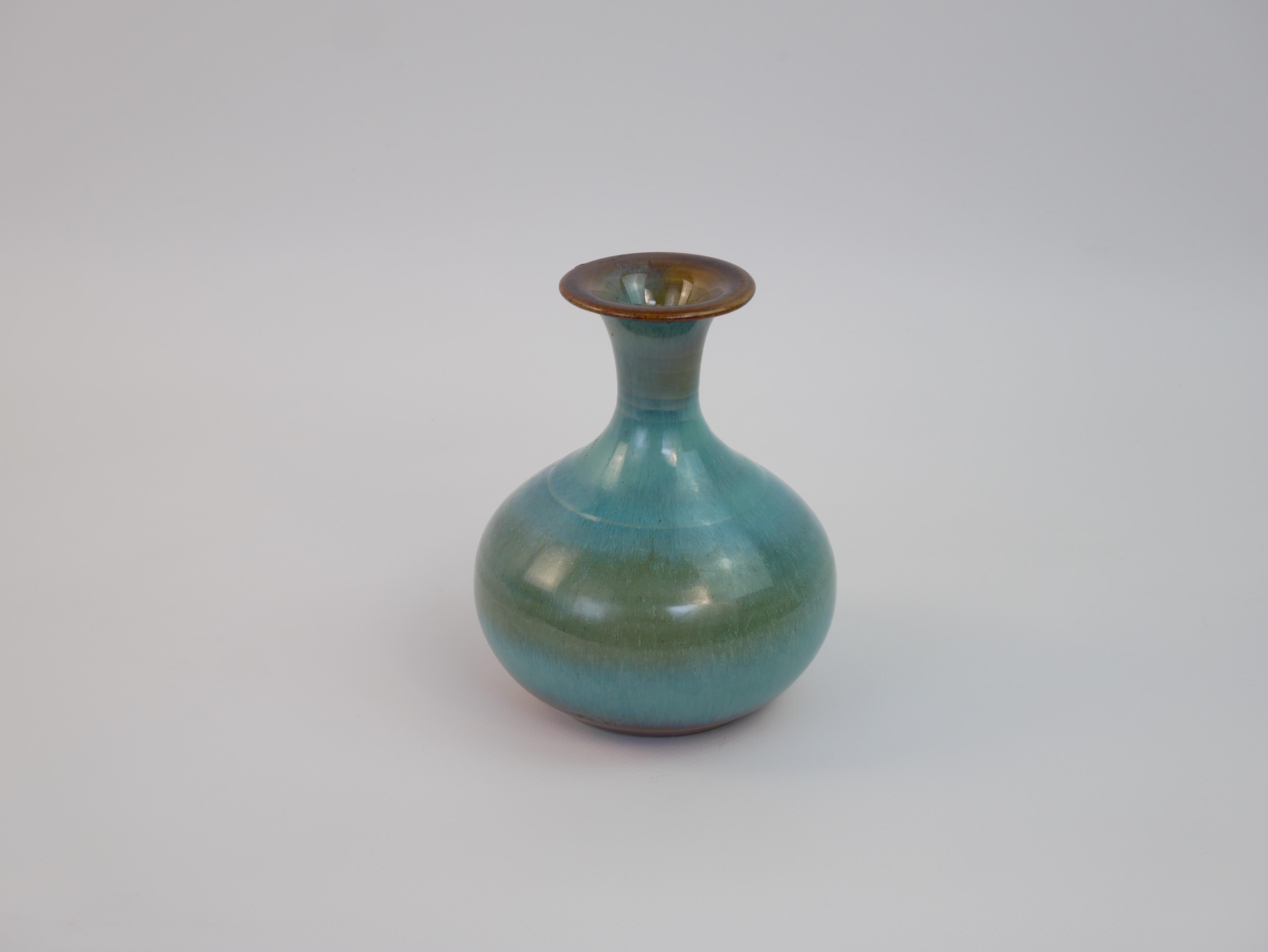 Certainement ! Voici une description du vase en 140 mots en anglais :

Il s'agit d'un petit vase élégant au design intemporel, attribué à l'artiste céramiste Guy-Roland Marcy. Il se caractérise par un corps arrondi qui se rétrécit en un col mince,