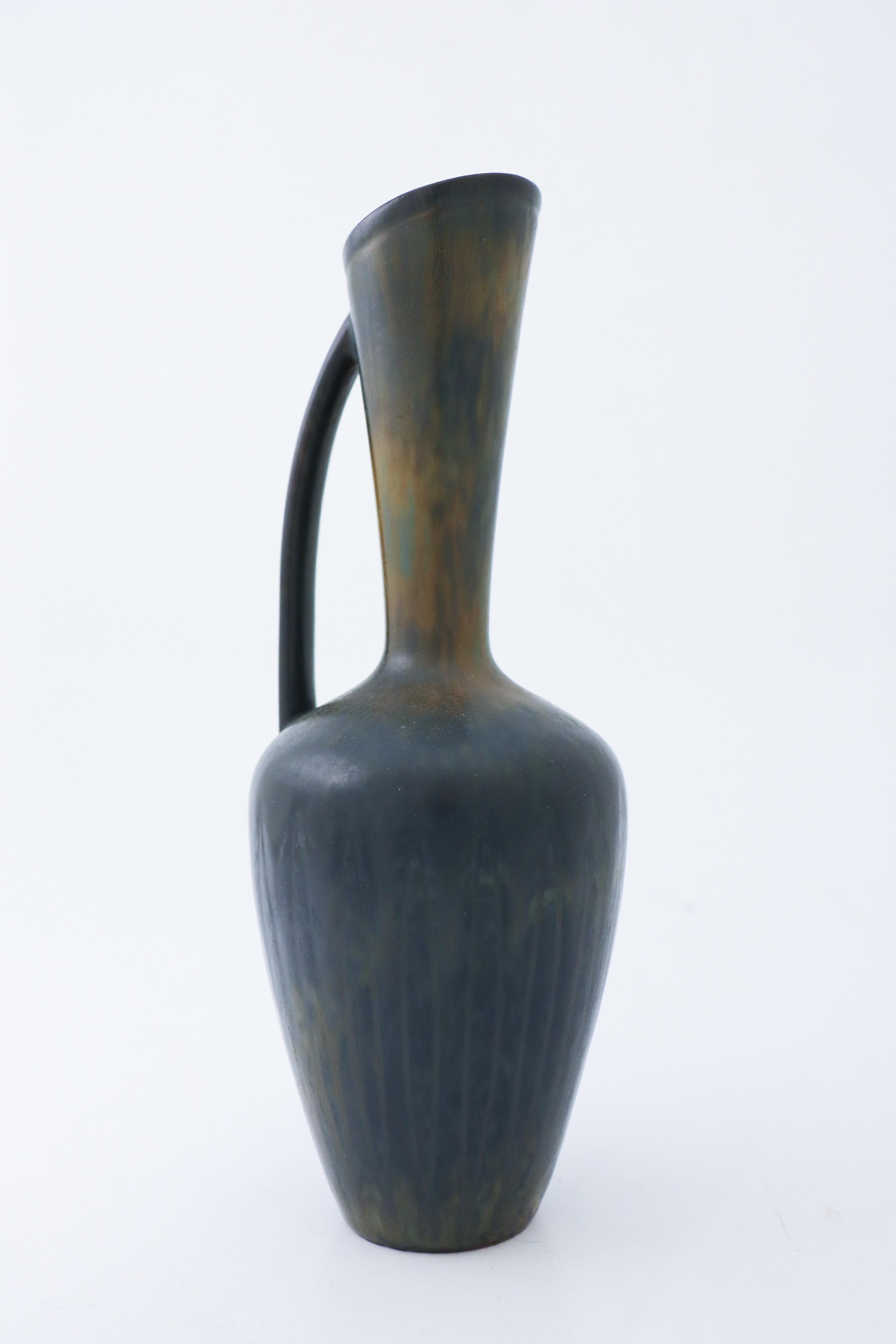 A vase with a handle designed by Gunnar Nylund at Rörstrand. The vase has a lovely black and green color. It is 27.5 cm high and in very good condition. The vase is marked as 2nd quality, I cannot see why. 

