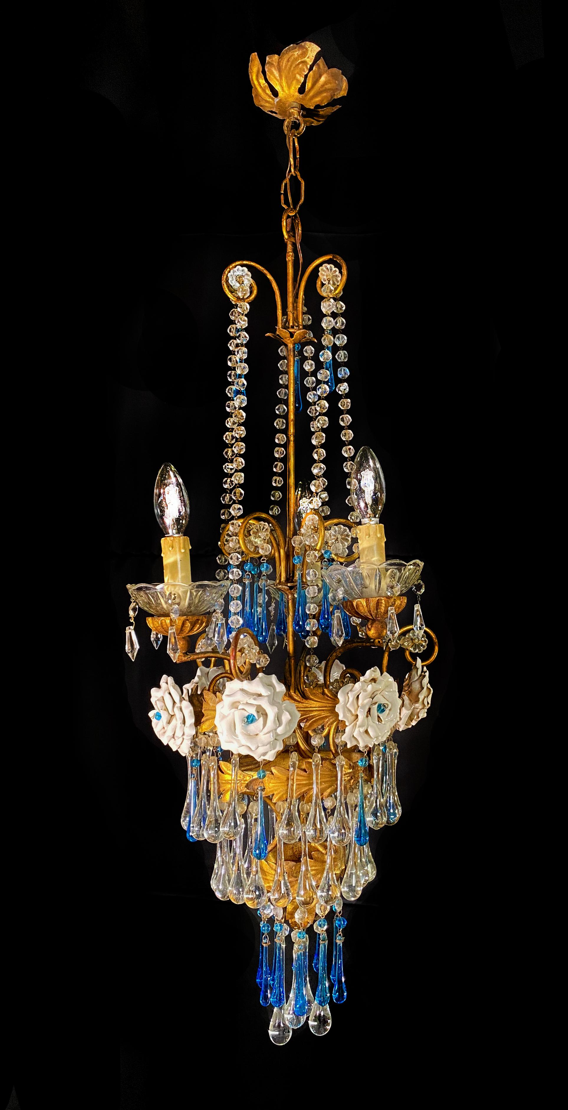 Eleganter venezianischer Kronleuchter. Blaue Tropfen und 6 Rosen hängen von dem goldenen Baldachin. 3 kleine Lichter.
.  