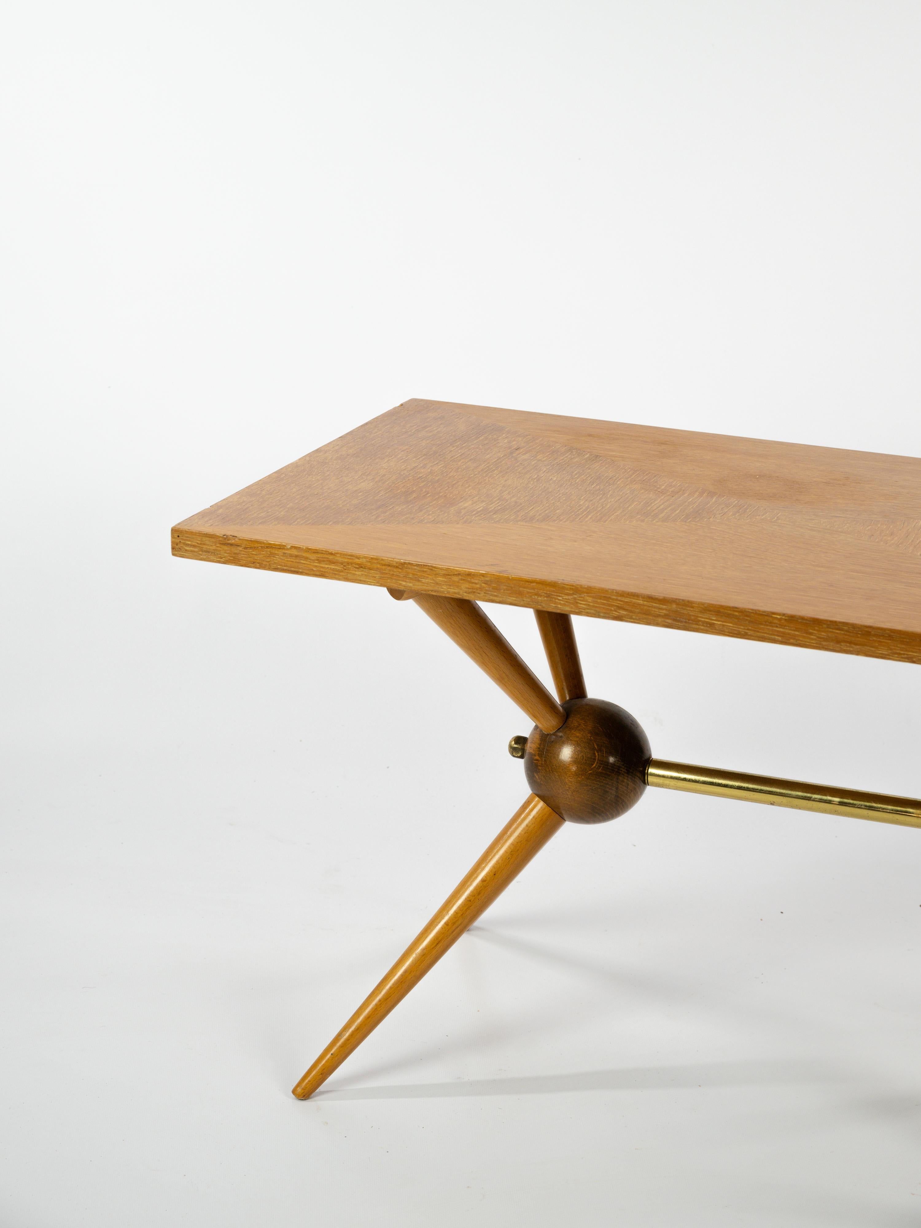 Jolie table basse en bois clair avec un magnifique plateau en placage bois. 

La forme du pied Sputnik donne un aspect unique à cette table. 

Les détails en laiton sont typiques de la période du milieu du siècle. 

Ouvrage français vers 1960.