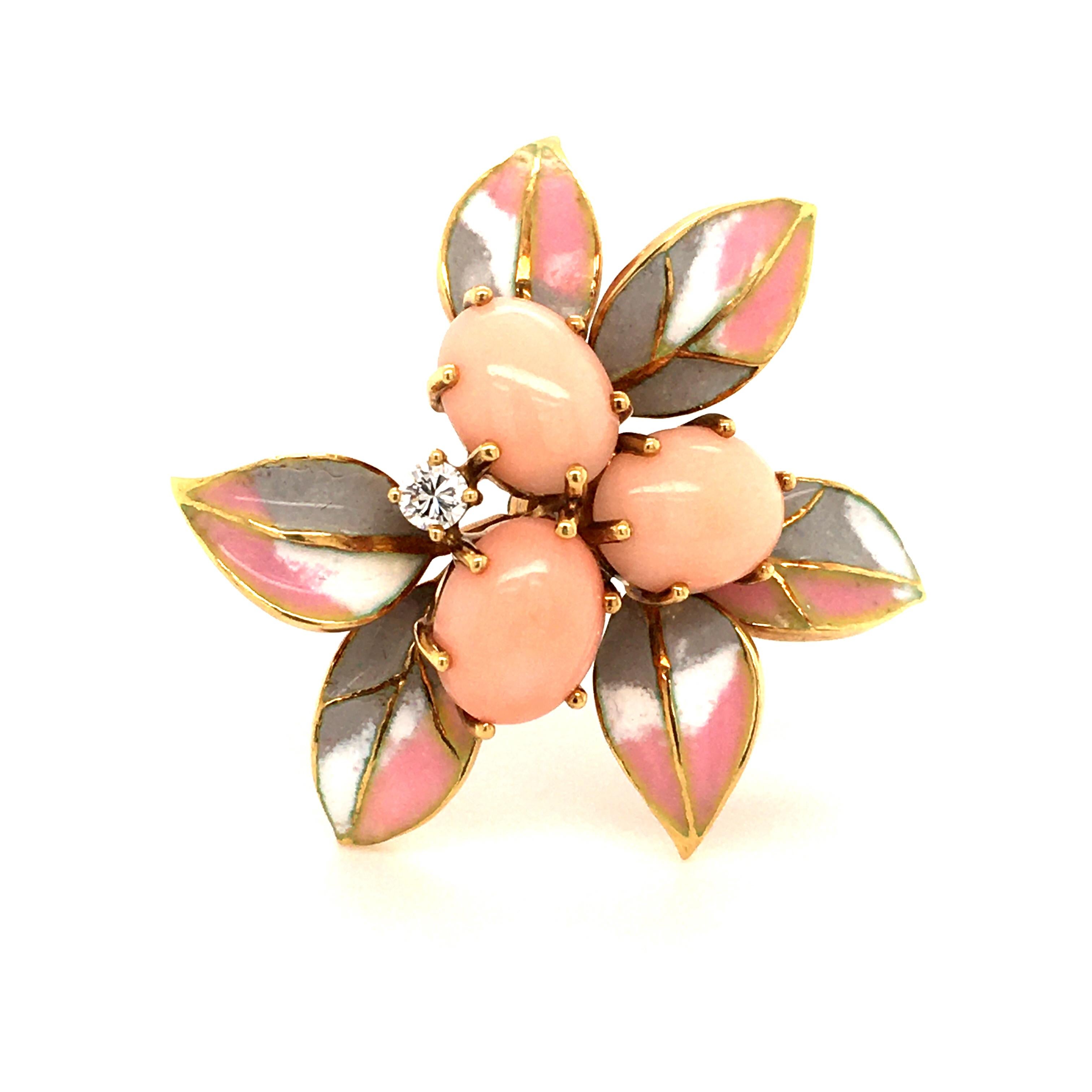 This elegant flower brooch in 18 karat yellow gold features three oval cabochon shaped corals and one brilliant cut diamond of 0.09 carats, G/H color and vs clarity. The leaves are softly enameled in the colors rose, gray, and white. A very lovely