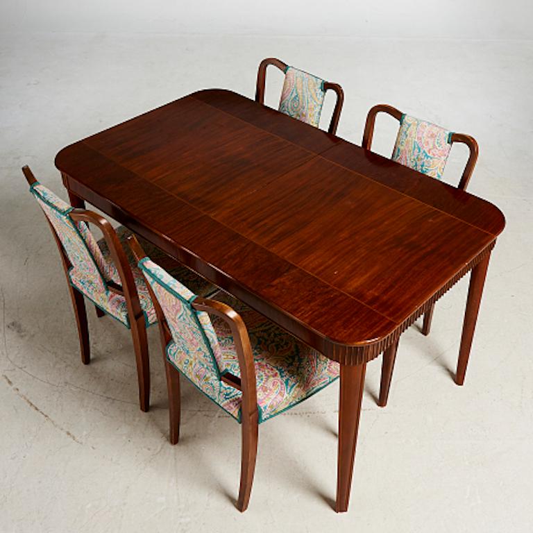 This set includes a dining room table that includes an attachment. The table is approximately 53 inches long, but the extension adds 16 inches, making it nearly 70 inches in length. The width is approximately 32 inches.

The four chairs have