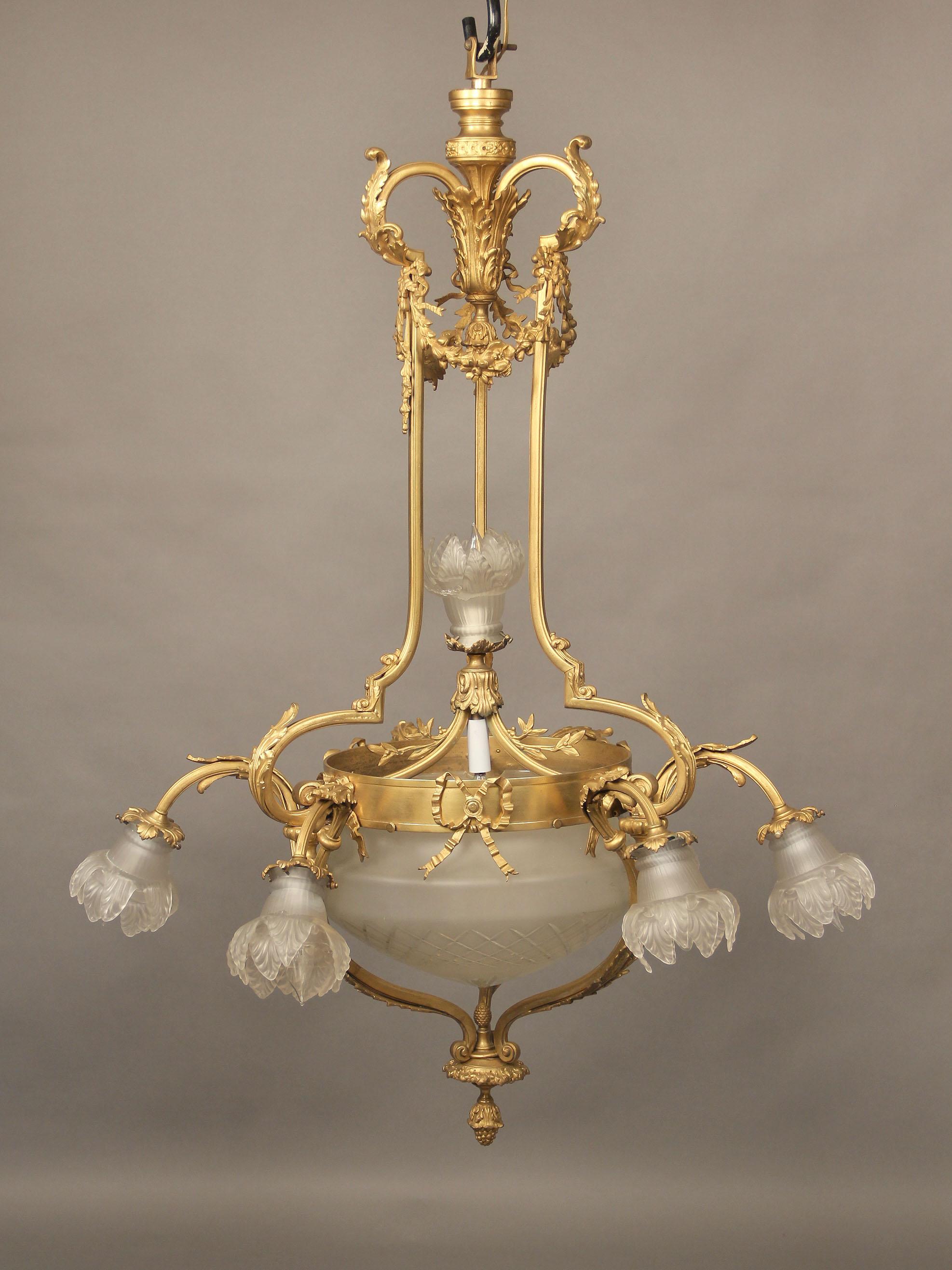 A lovely early 20th century gilt bronze eight-light chandelier

A gilt bronze frame with casted scrolled arms extending to six perimeter lights with rose shades, the bottom centered with crystal bowl. The top with bronze flowers and bows. Two