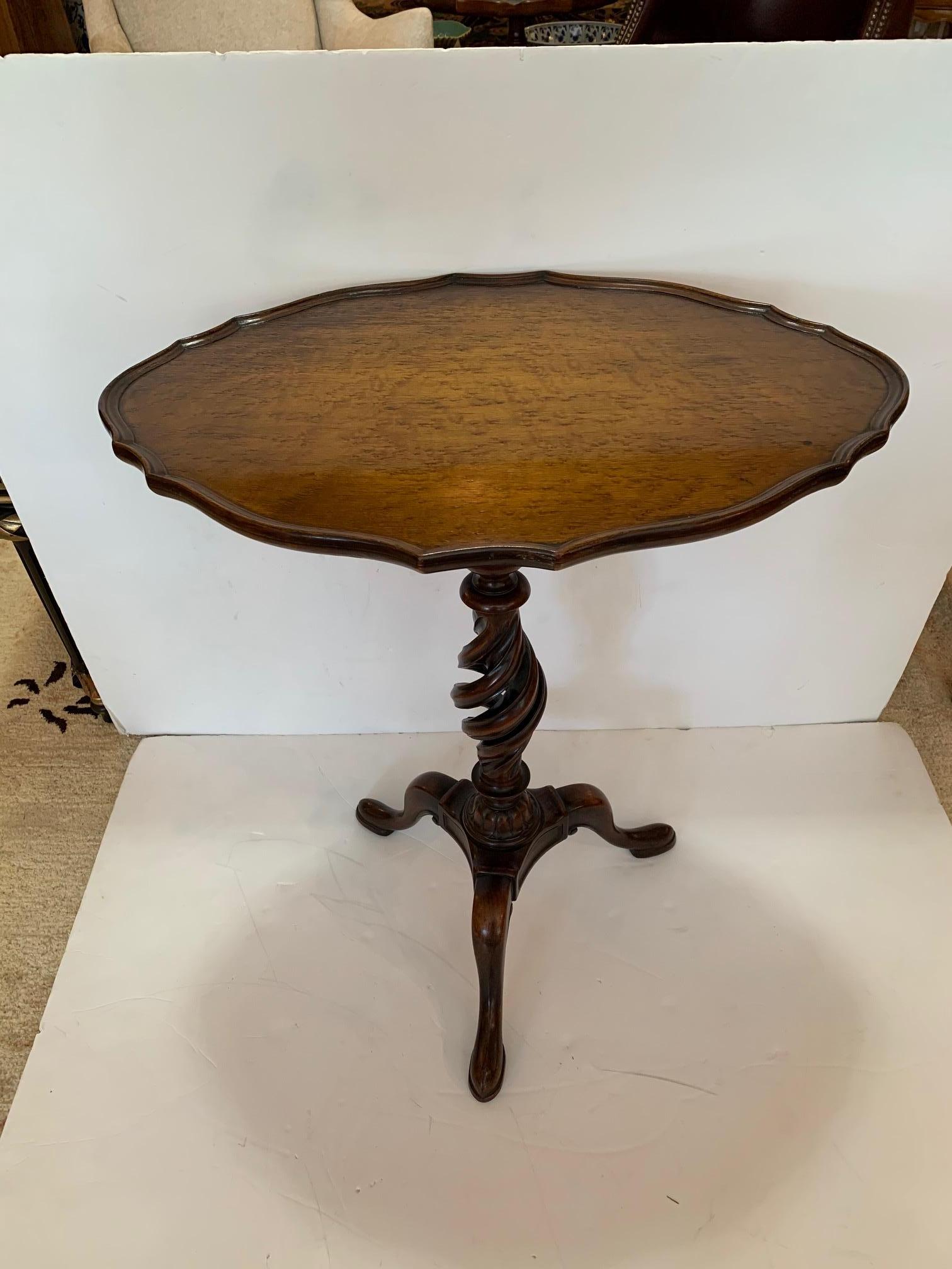 Beautiful antique English mahogany and burlwood oval side table having a pie crust scalloped top and barley twist base with tripod feet.
  
