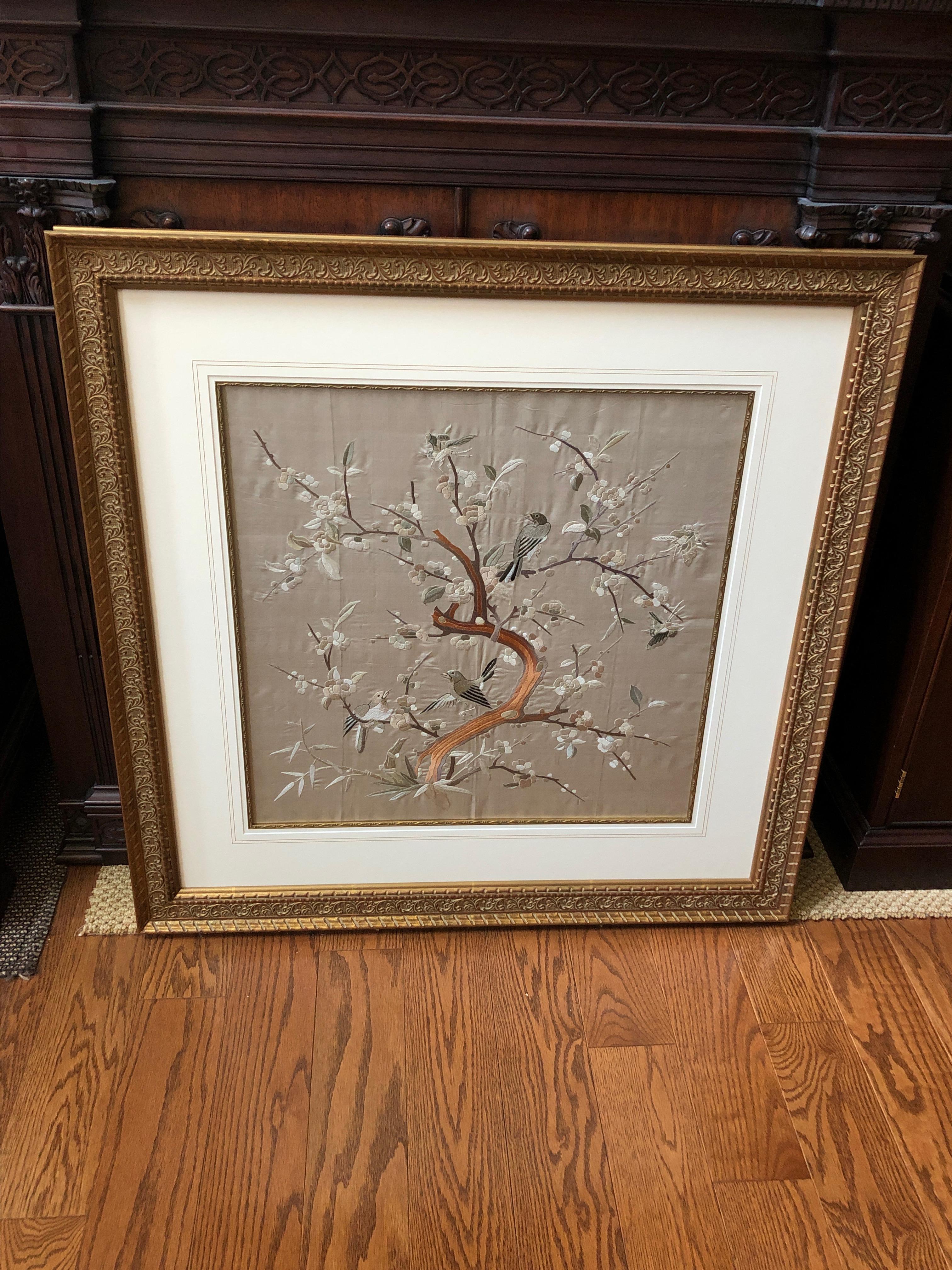 A beautifully refined piece of wall art consisting of a framed vintage Japanese embroidery having lovely grey silk background with birds and foliage. The textile is framed exquisitely with interior gold filet, wide linen mat and giltwood molding.