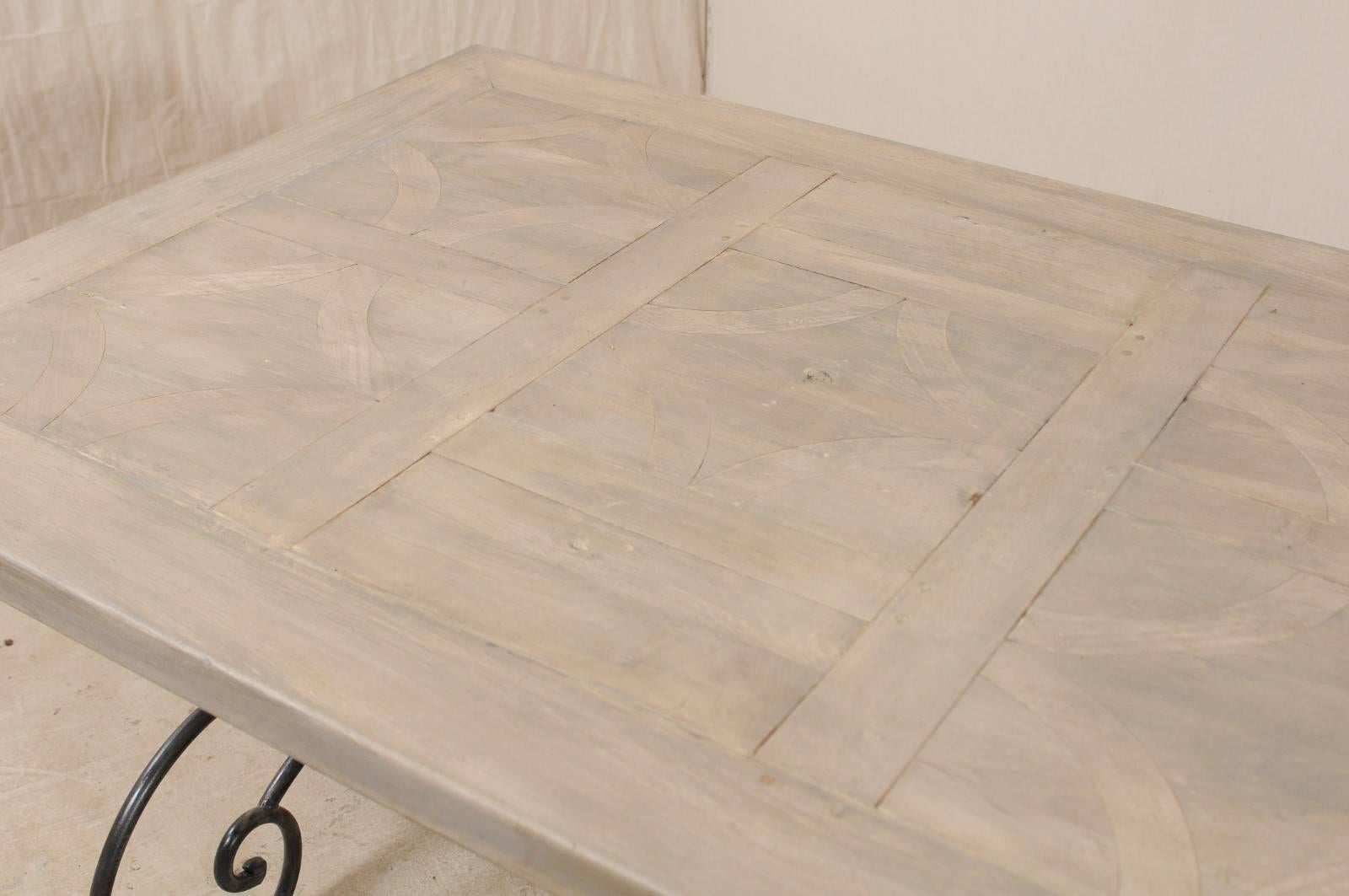 Mesa francesa de época con tablero de madera con incrustaciones sobre una hermosa base de hierro con volutas en venta 2