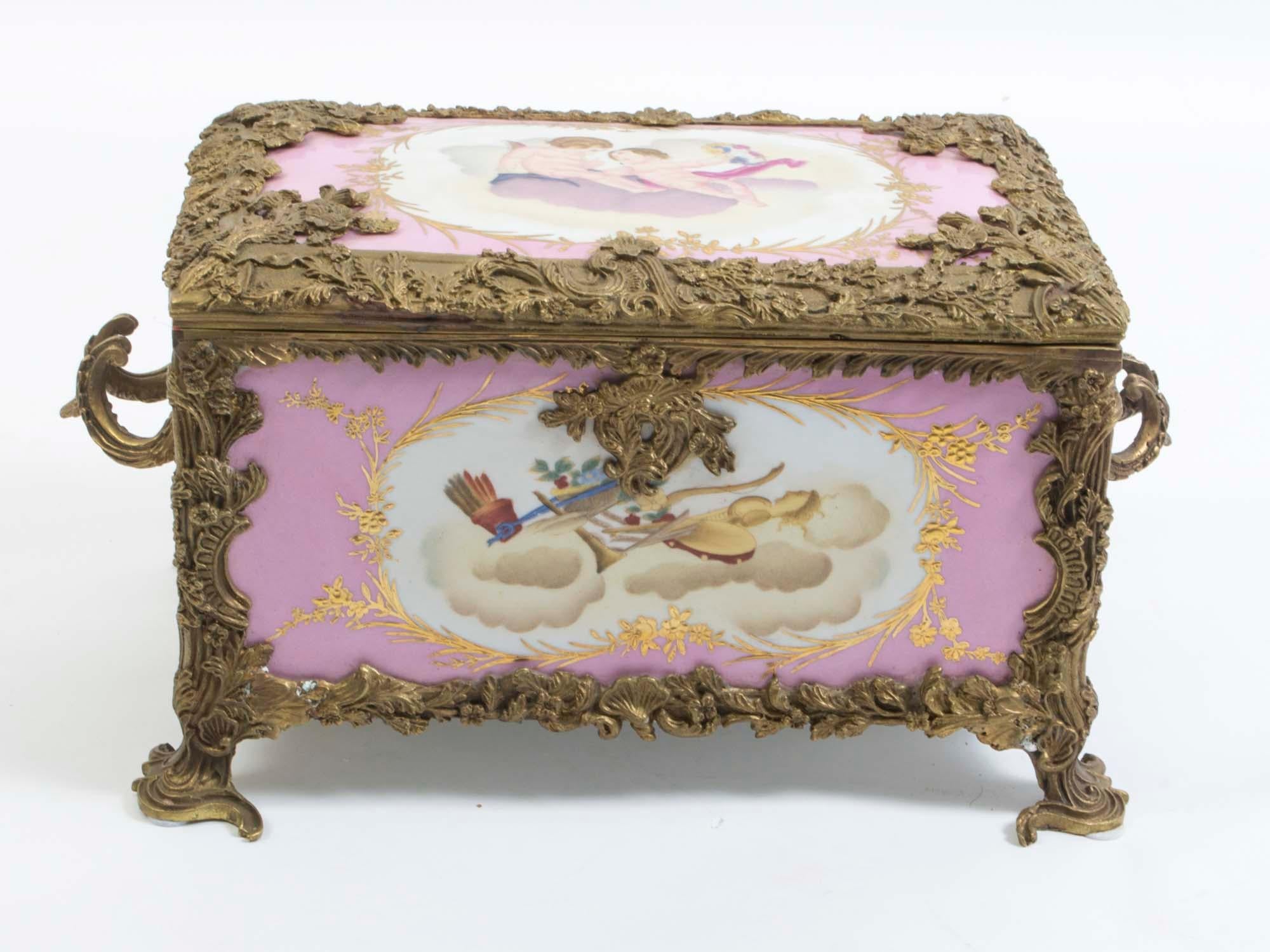 This is a beautiful large French Sevres style porcelain and ormolu-mounted jewelry casket in a powder pink, from the last quarter of the 20th century.

This highly decorative piece is hand painted with cherubs and musical instruments. It is